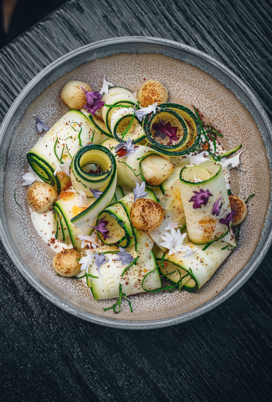 Elegant zucchini ribbons dish with edible flowers for event catering.