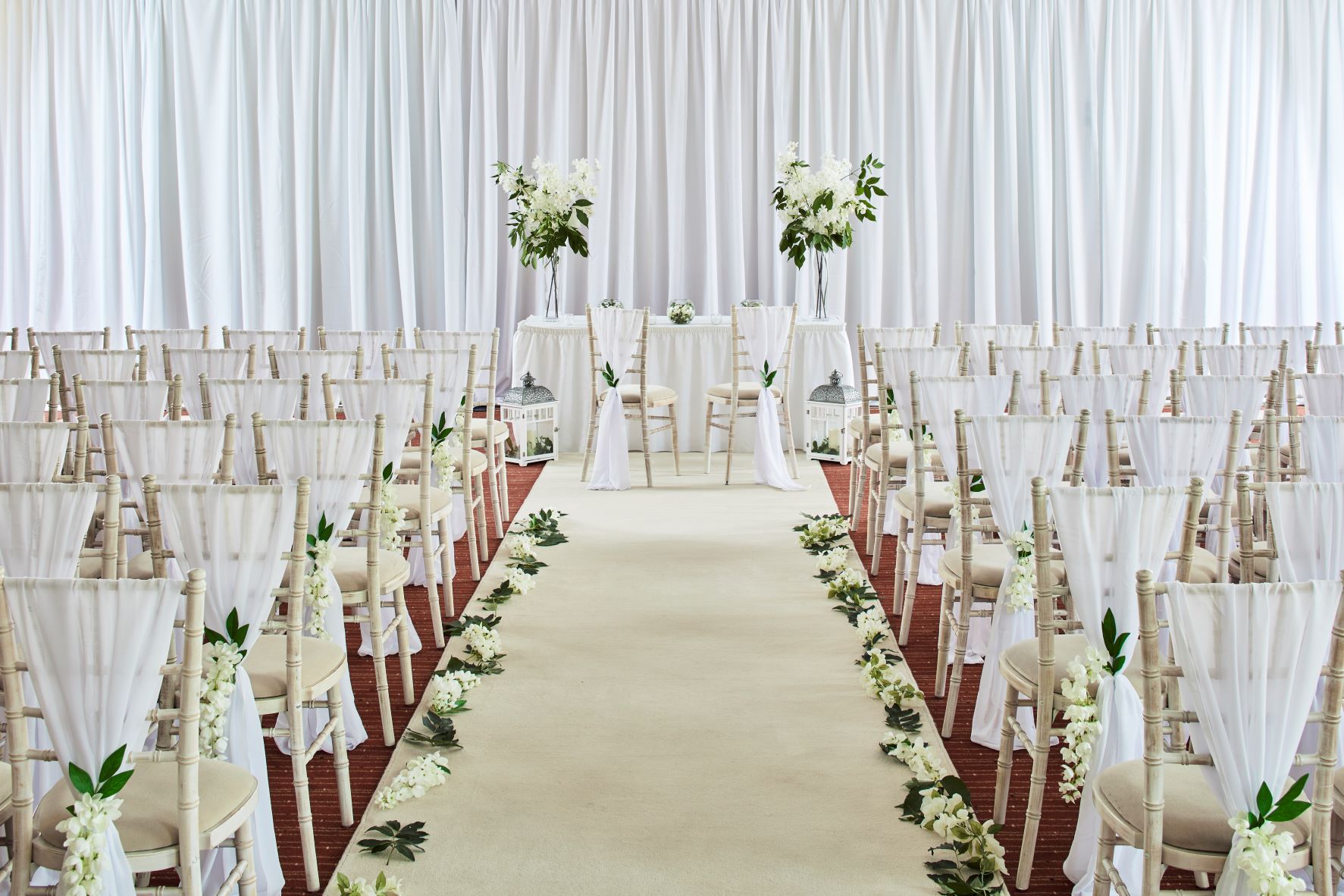 Wedding ceremony setup in Heritage Suite, Portsmouth Marriott with floral aisle and elegant chairs.