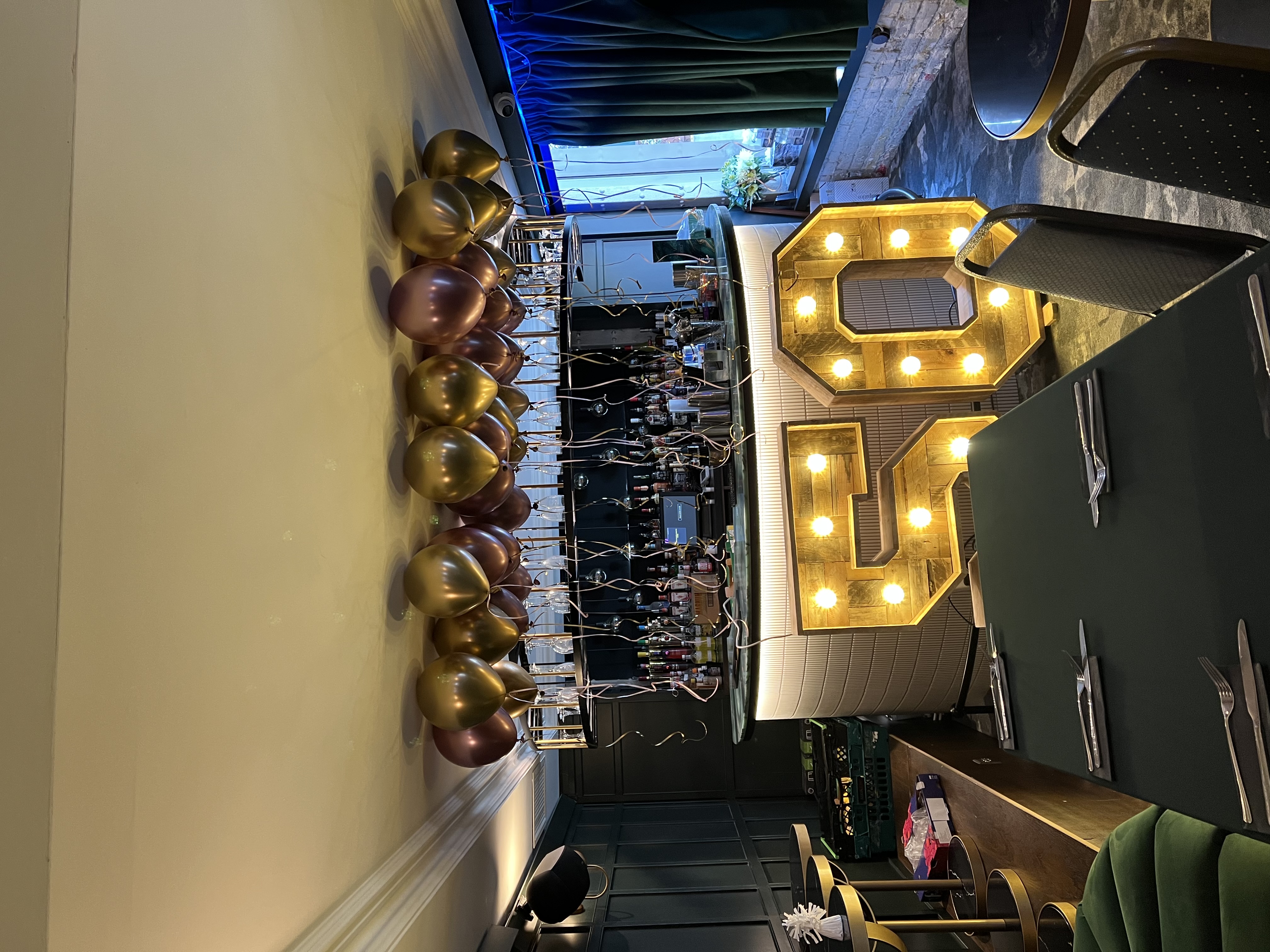 Elegant lounge with gold balloons and a "50" sign for milestone celebrations.