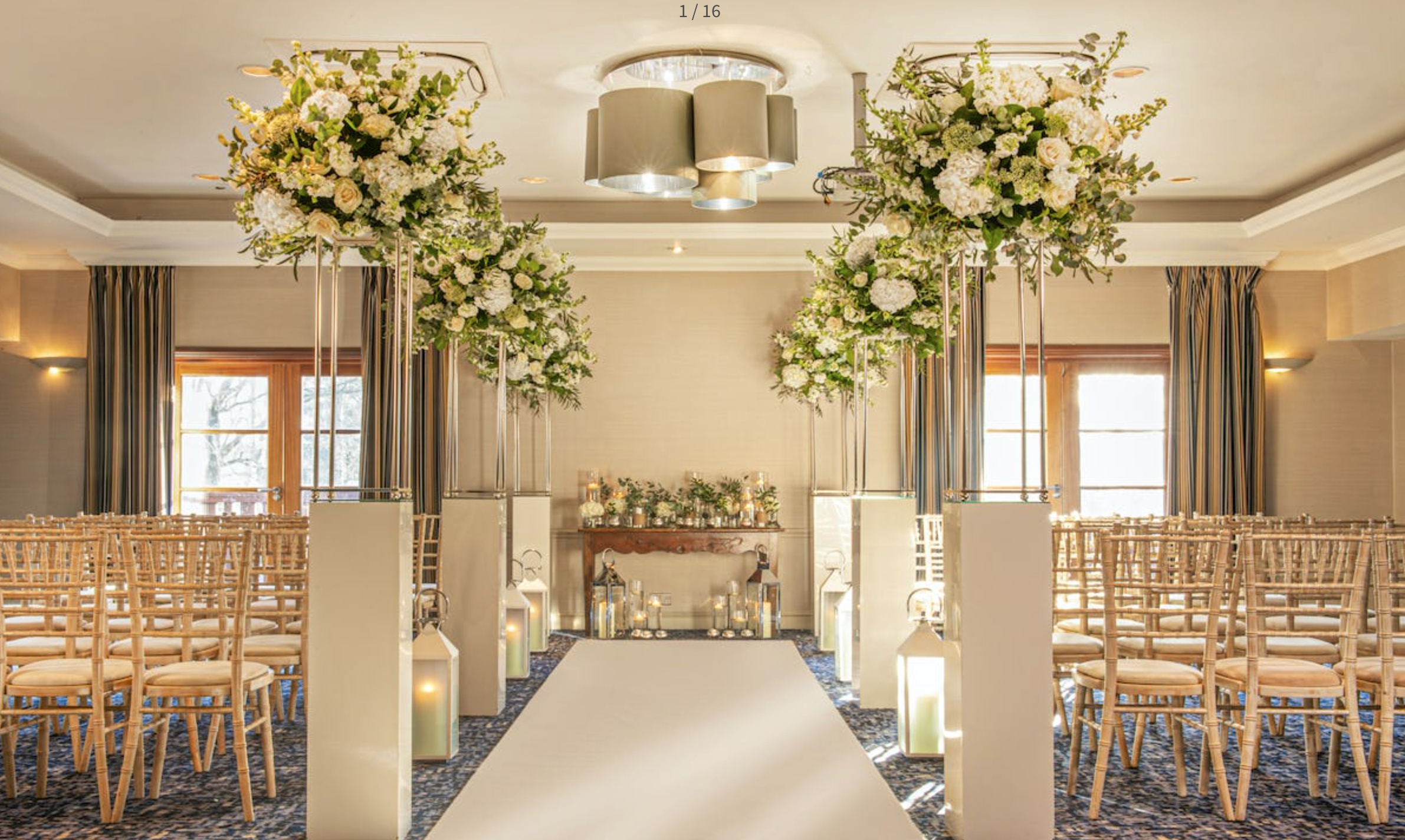 Elegant wedding ceremony setup in Hambledon suite, featuring tall floral arrangements.