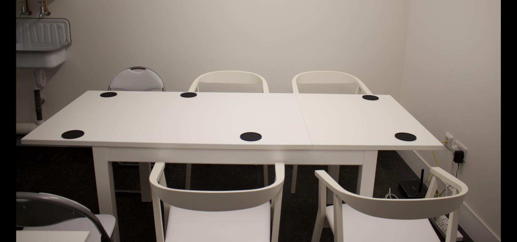 Minimalist podcast meeting room with white table and power outlets for creative discussions.