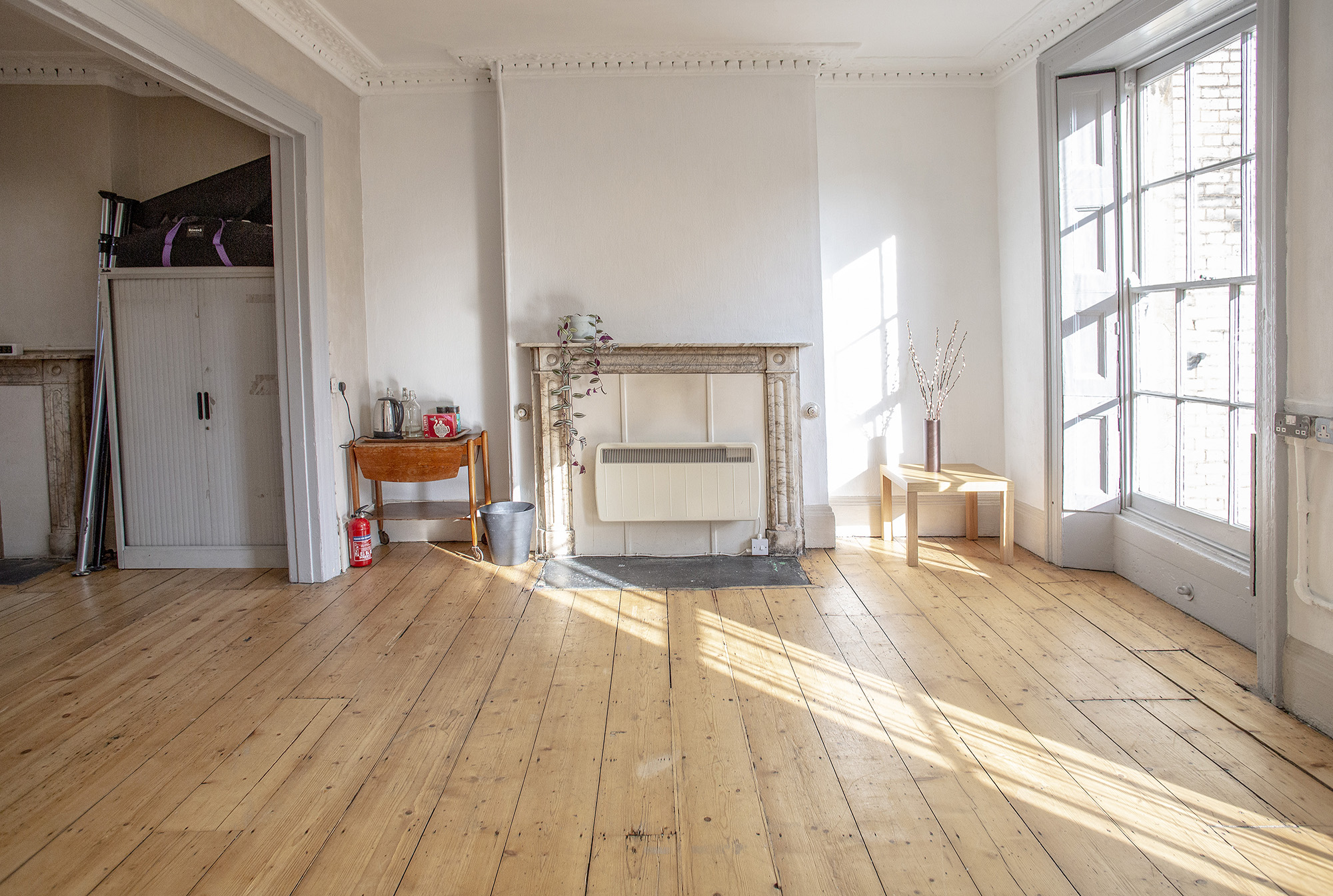 Spacious event space with wooden floors and fireplace, perfect for meetings and workshops.