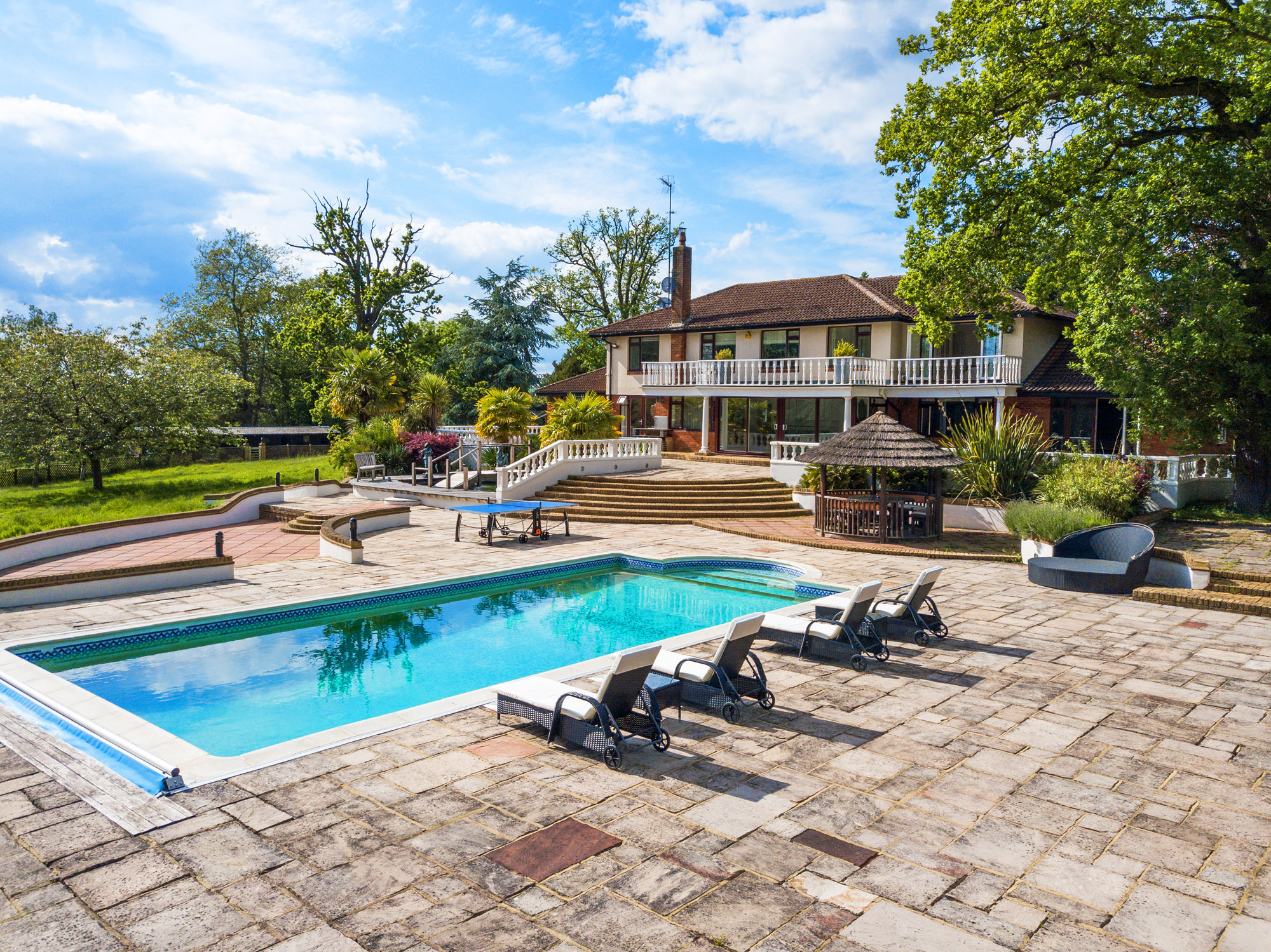 Outdoor event venue at The Villa Mansion with a spacious pool and lush greenery.