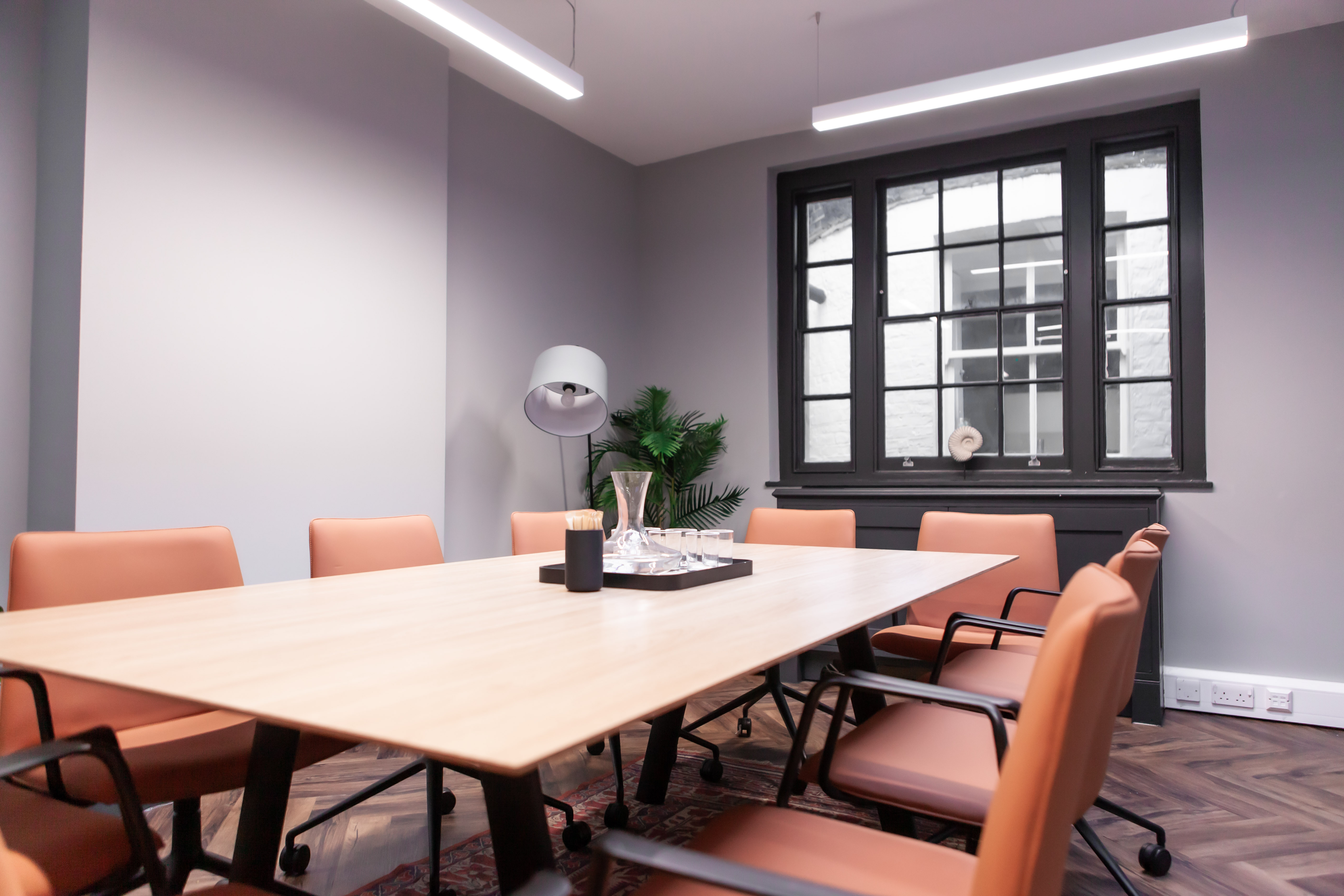 Modern meeting room with wooden table and orange chairs, perfect for collaboration sessions.