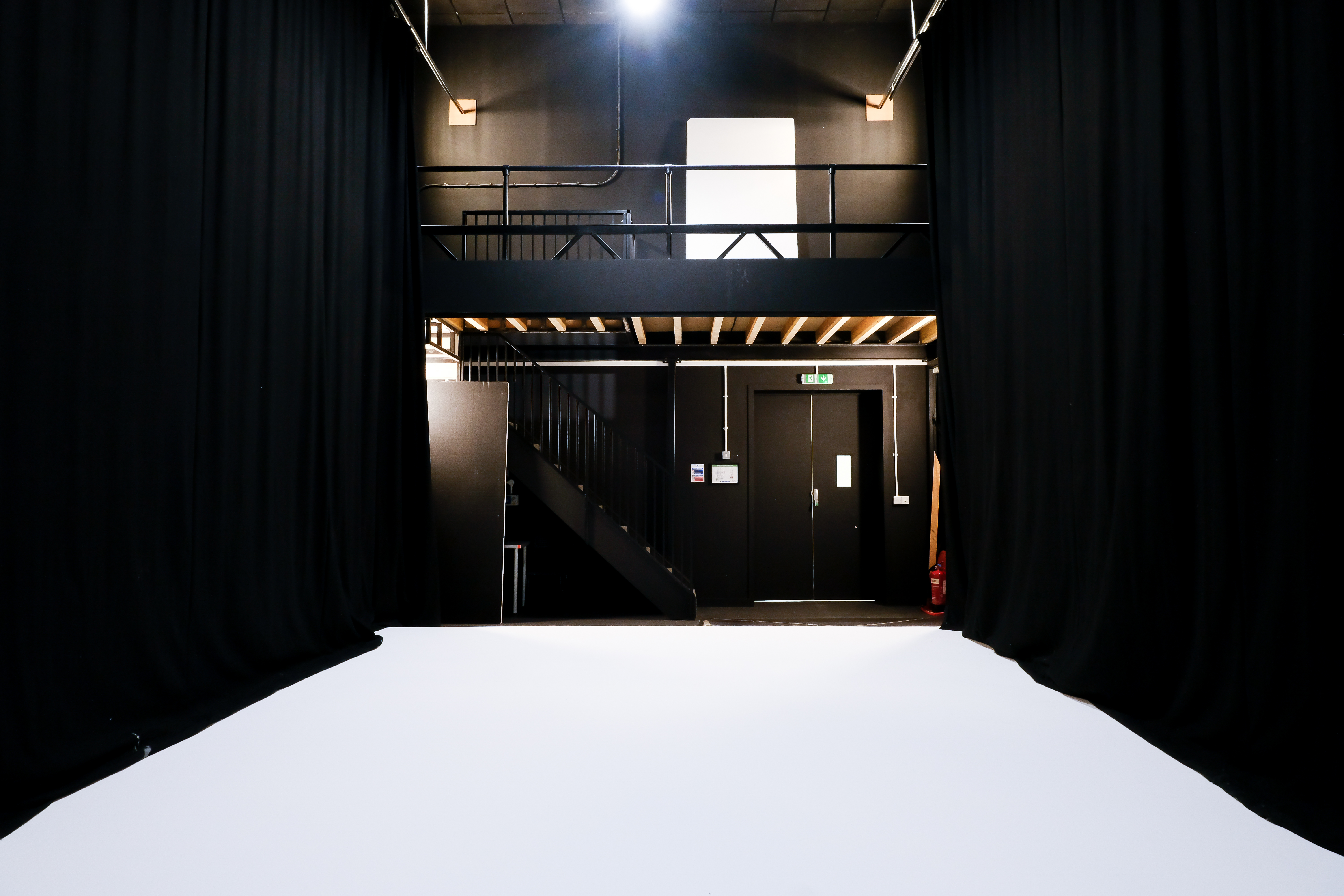 Versatile event space with white floor and black drapery, perfect for presentations and workshops.