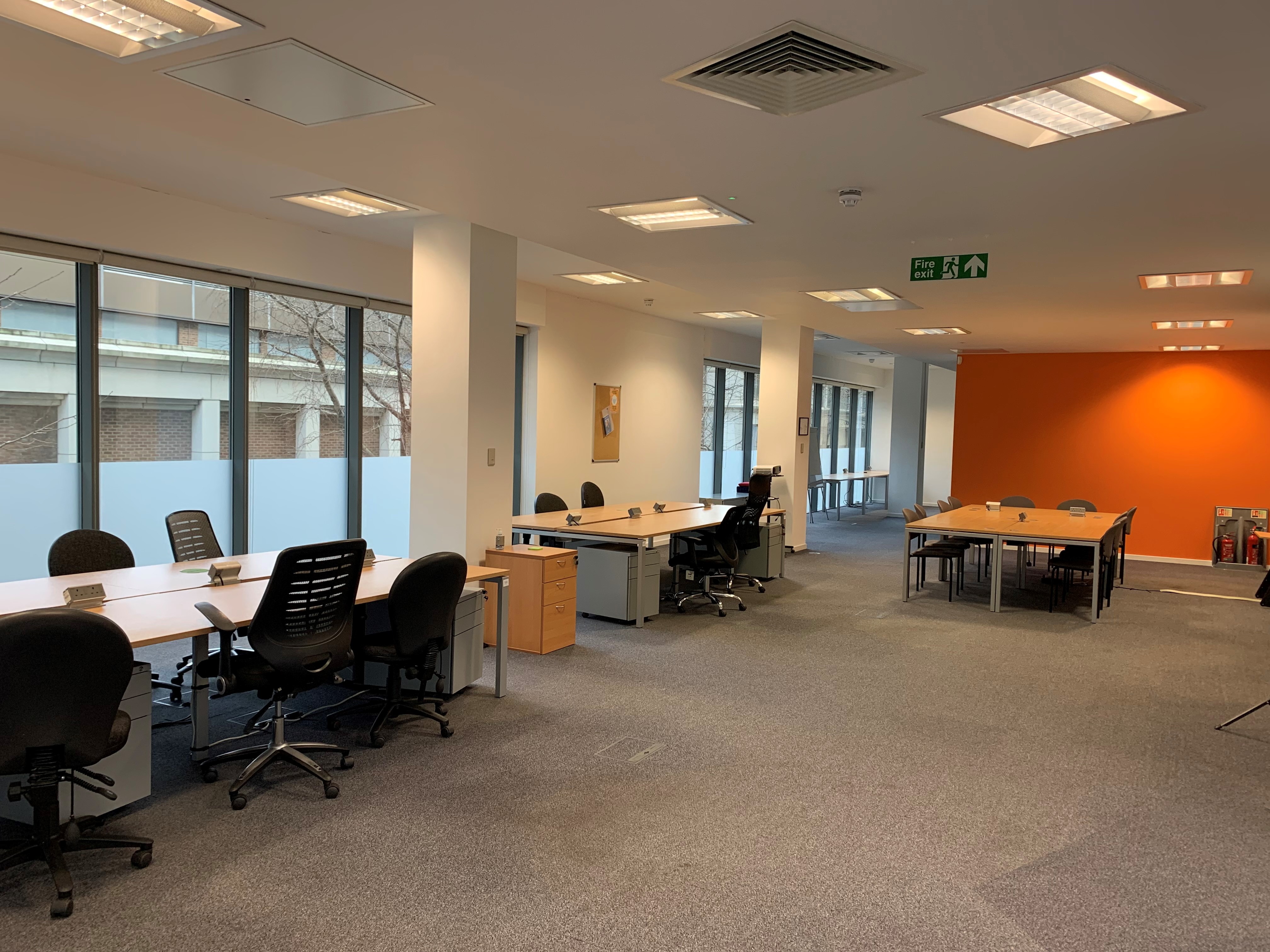 Versatile MDUK office meeting space with bright layout and orange accent wall.
