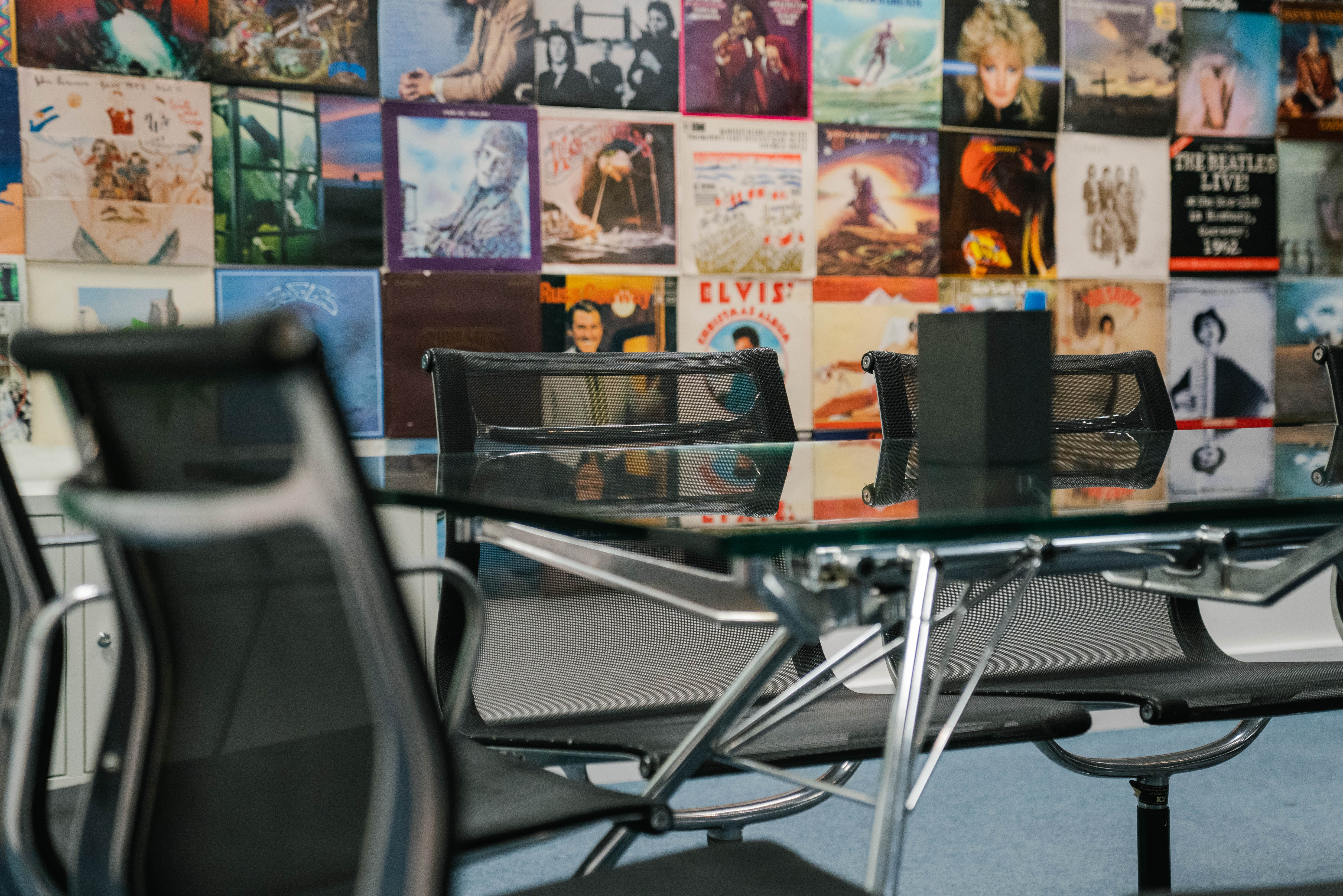 Modern meeting room with glass table and vintage album wall for creative brainstorming.