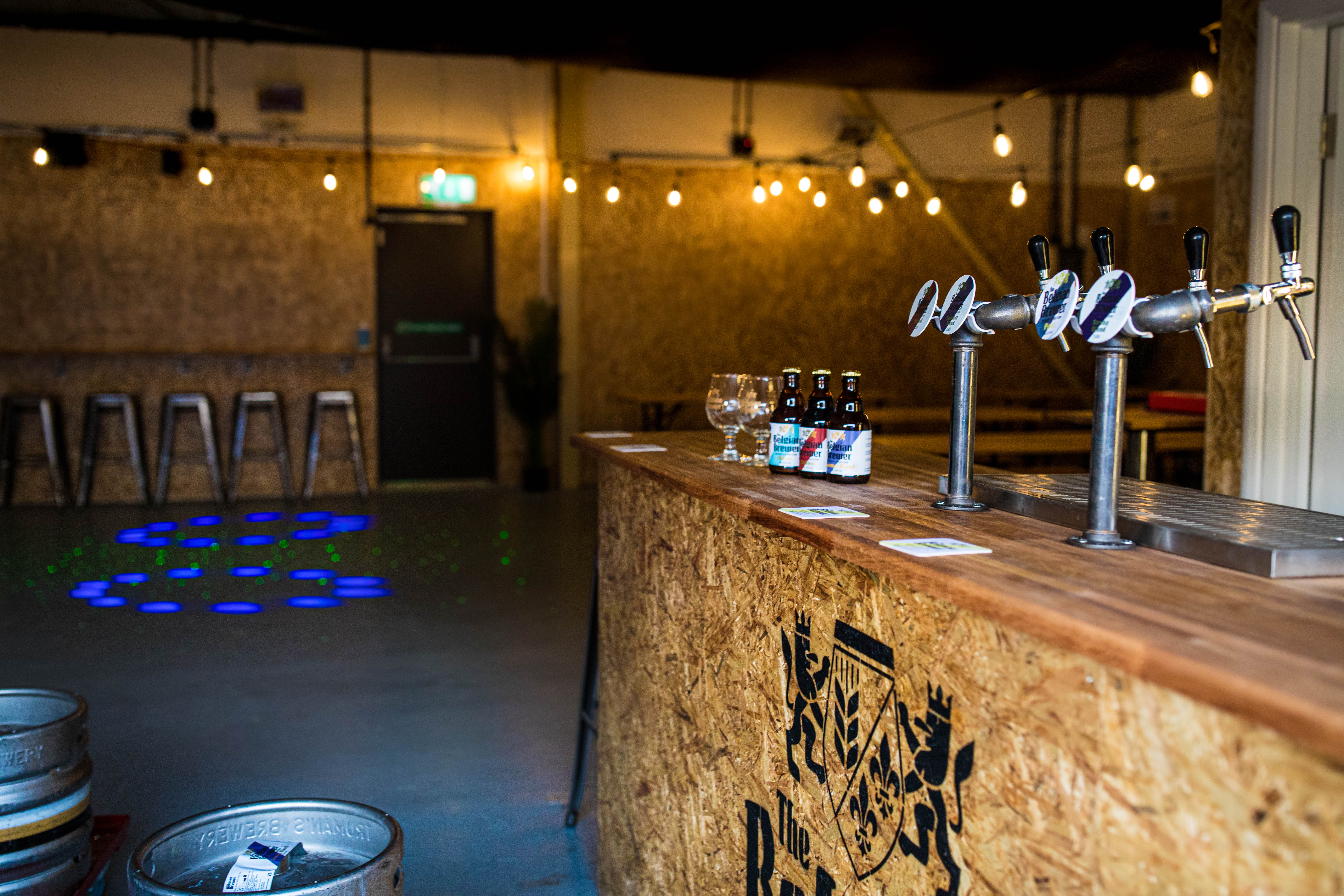 Stylish Belgian Brewer Event Hall with wooden bar, ideal for social gatherings and networking.