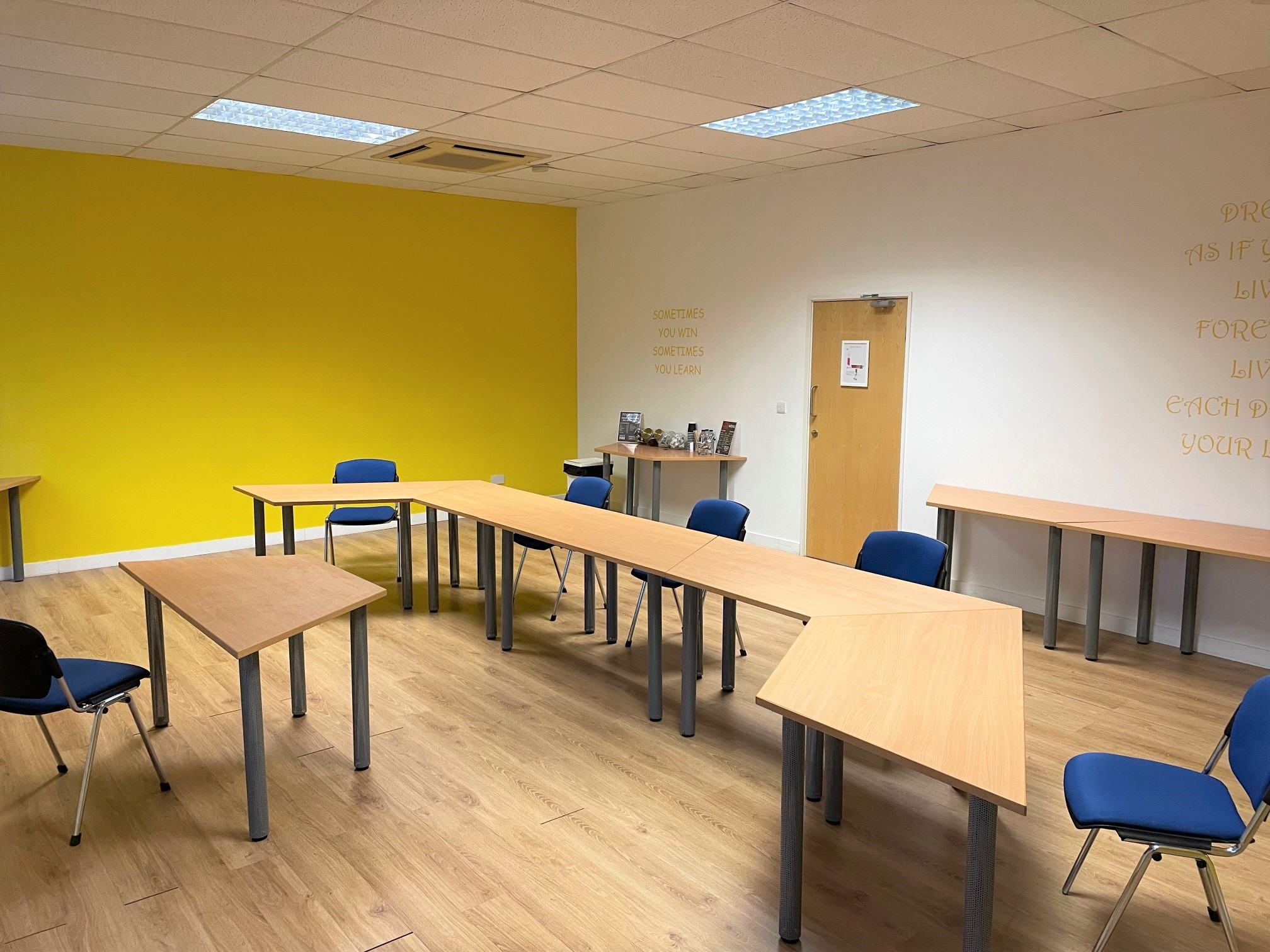 Versatile Yellow Room for workshops with modular tables and bright accent wall.