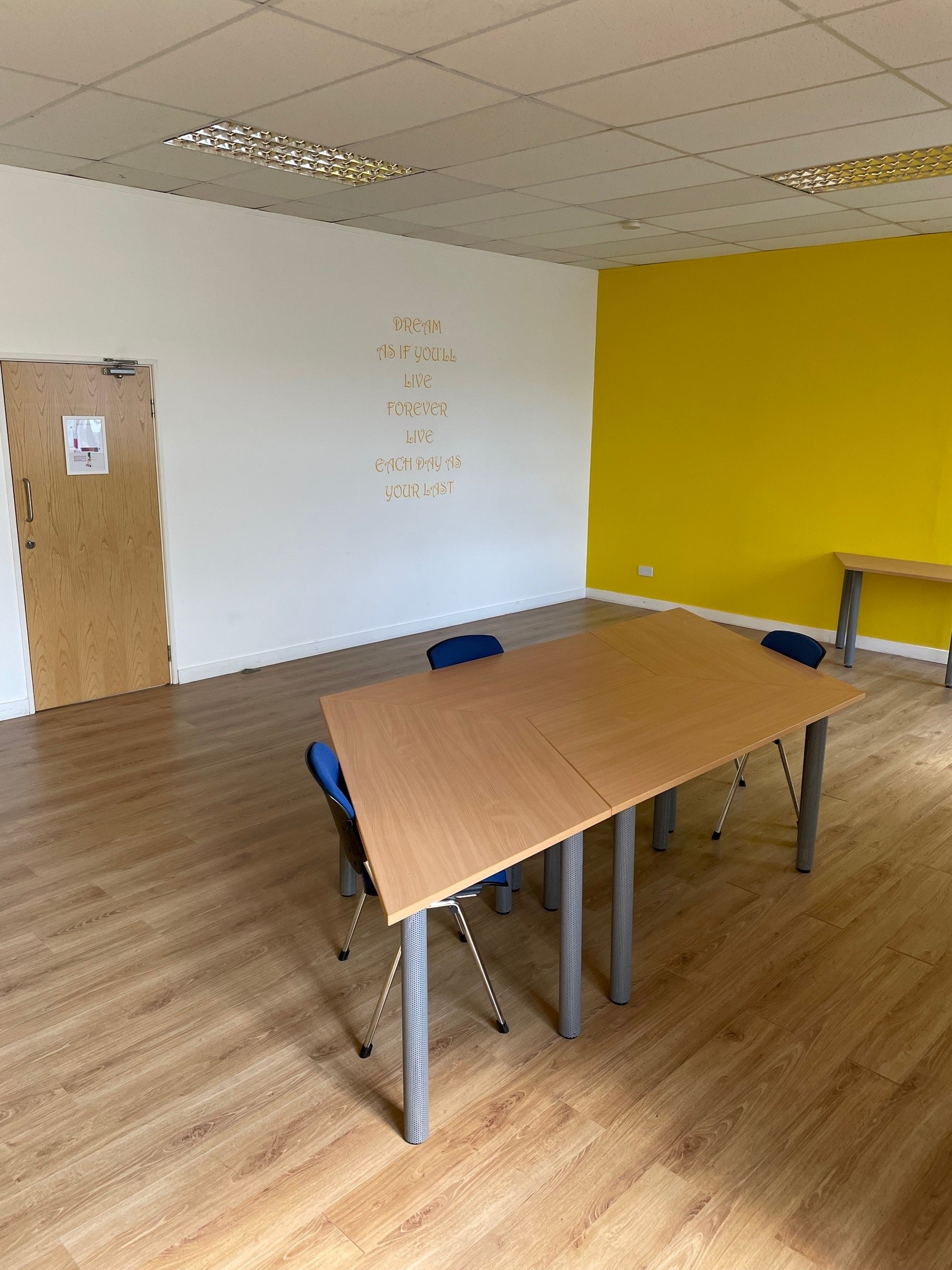 Versatile Yellow Room with wooden table, ideal for meetings and workshops.
