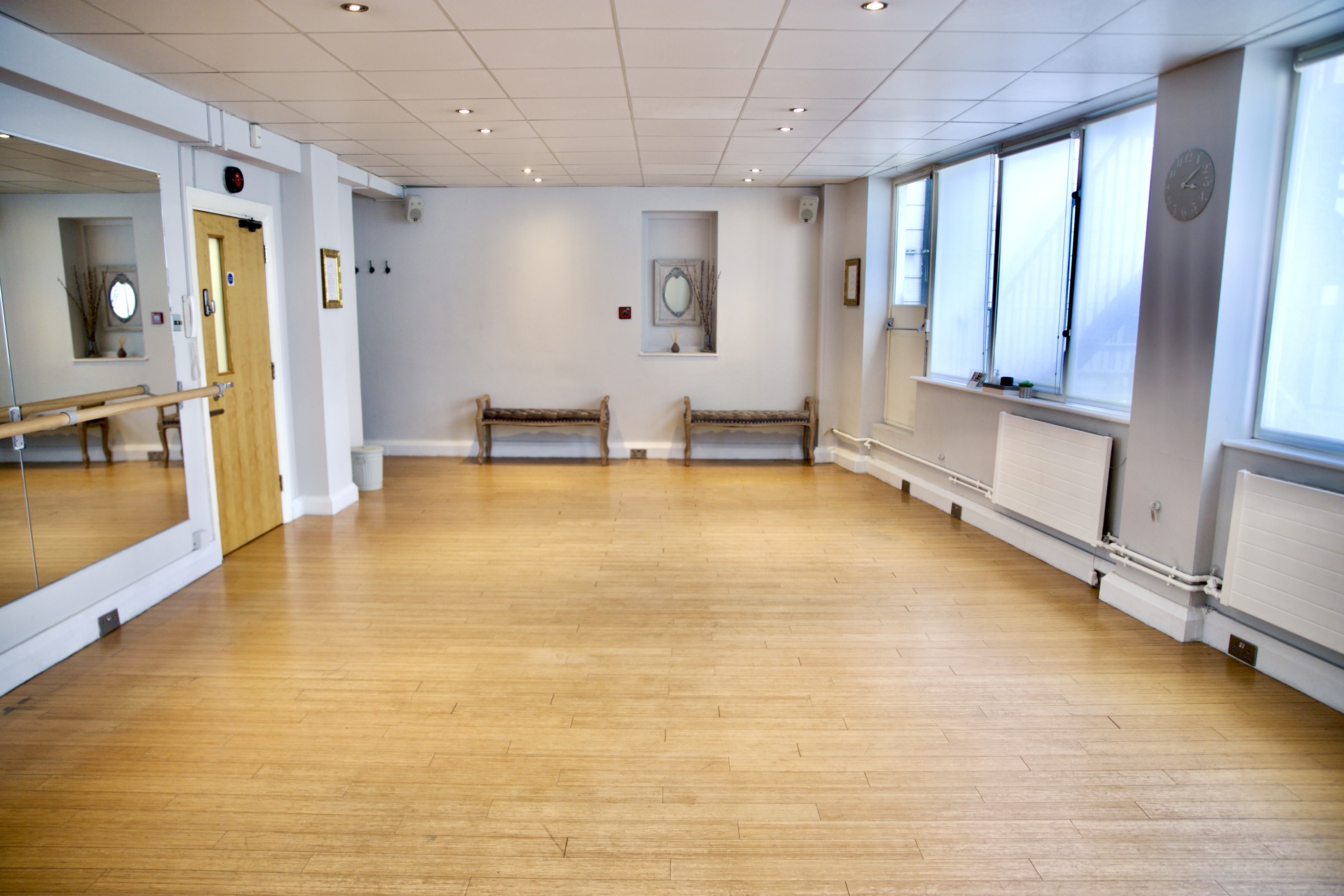 Spacious event space with wooden floors and mirrors, perfect for workshops and gatherings.
