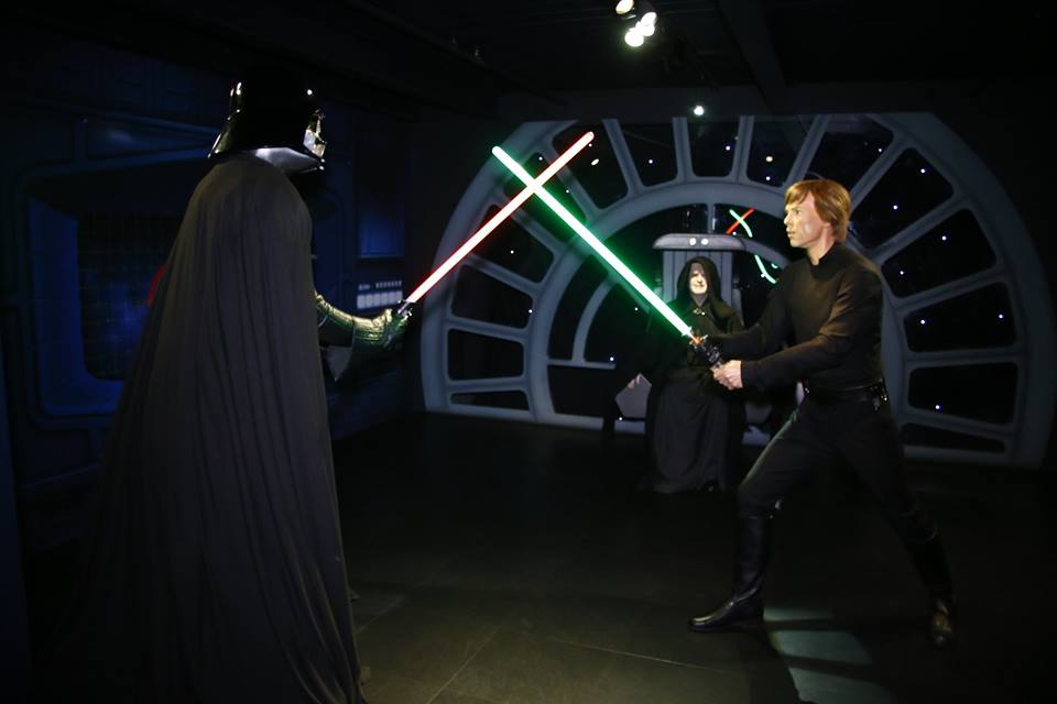 Iconic characters in lightsaber duel at Madame Tussauds for themed events.