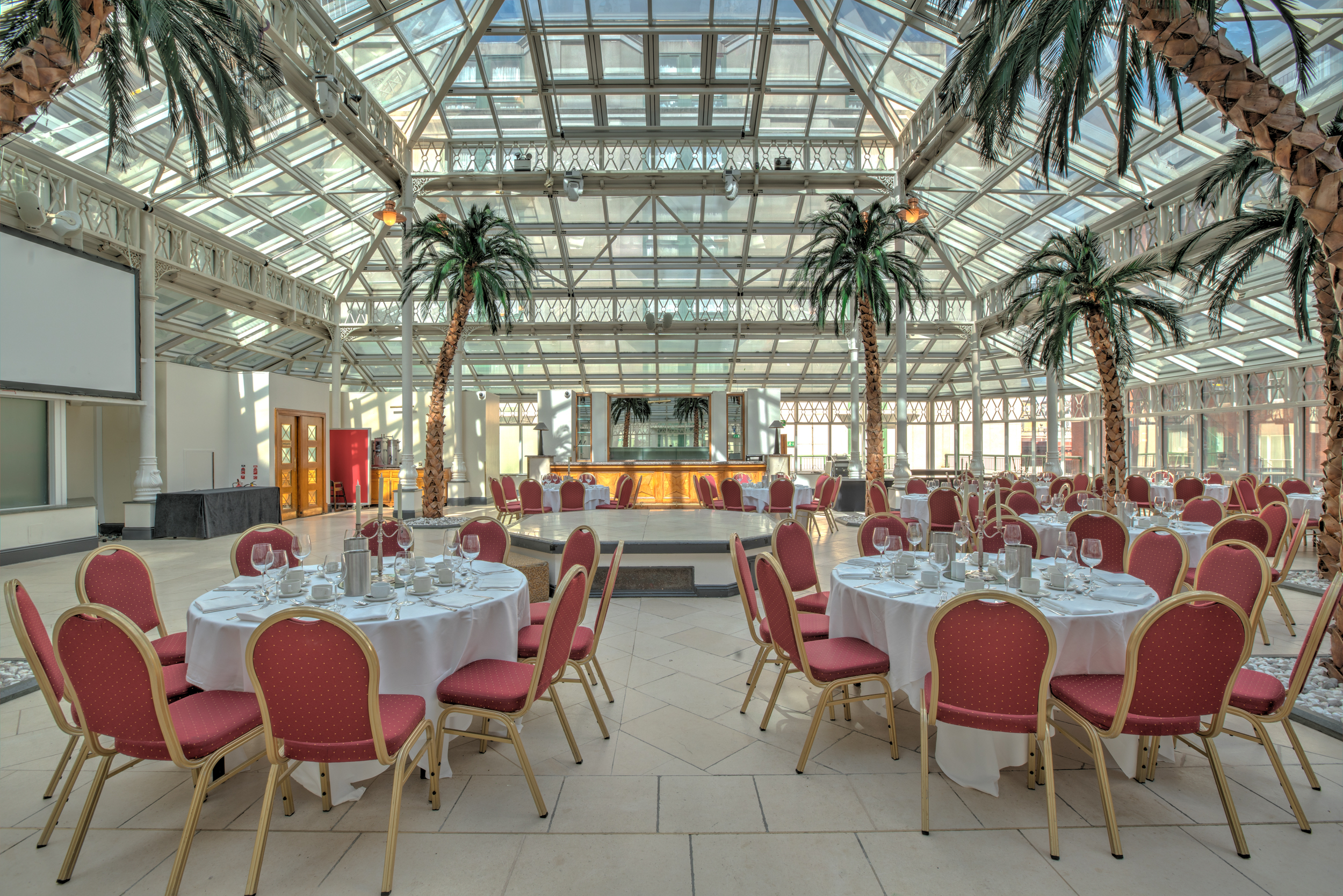 Elegant event space with round tables and glass ceiling in Kensington, London.