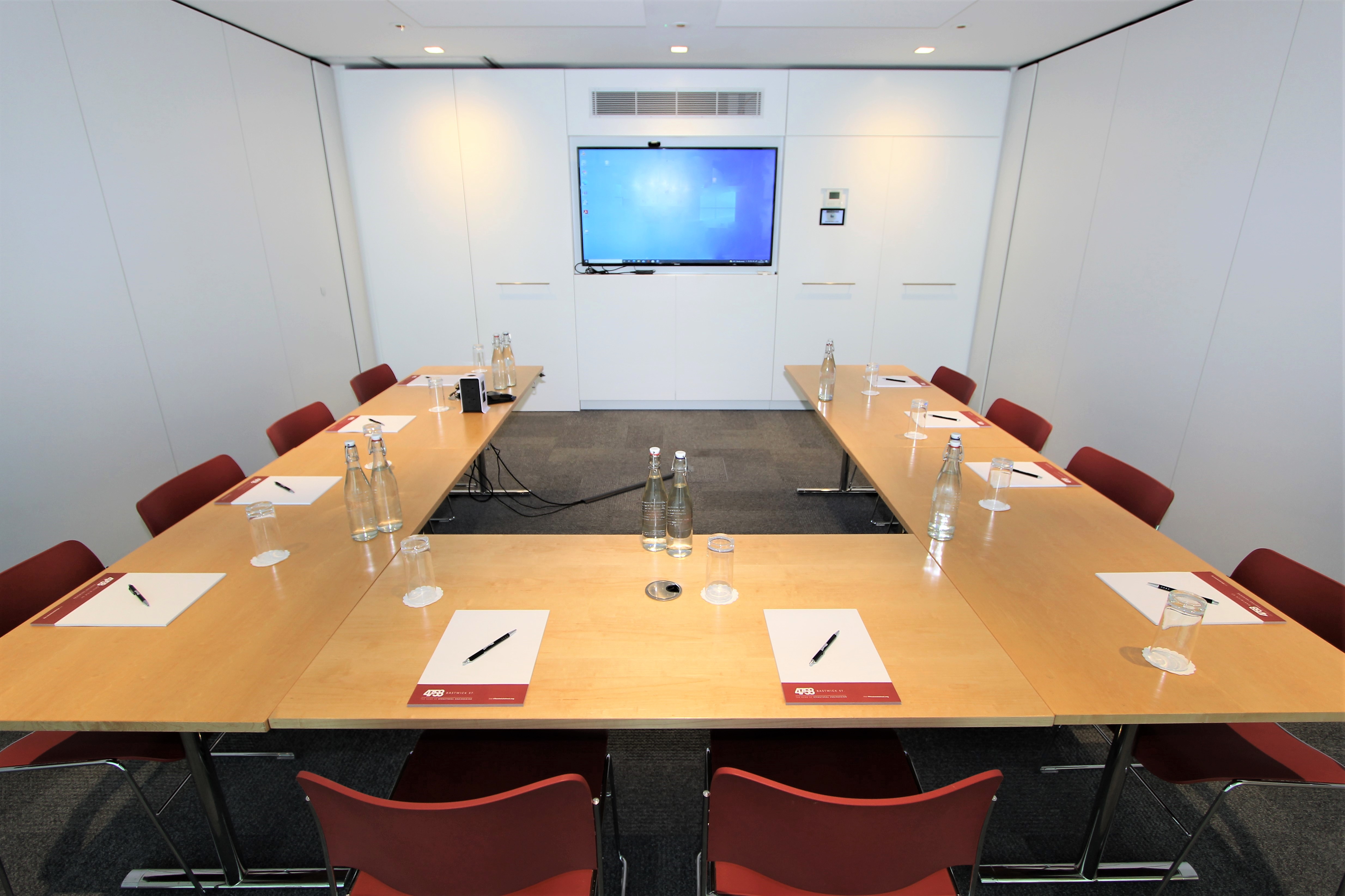 Meeting room with long table, notepads, and screen for professional events.