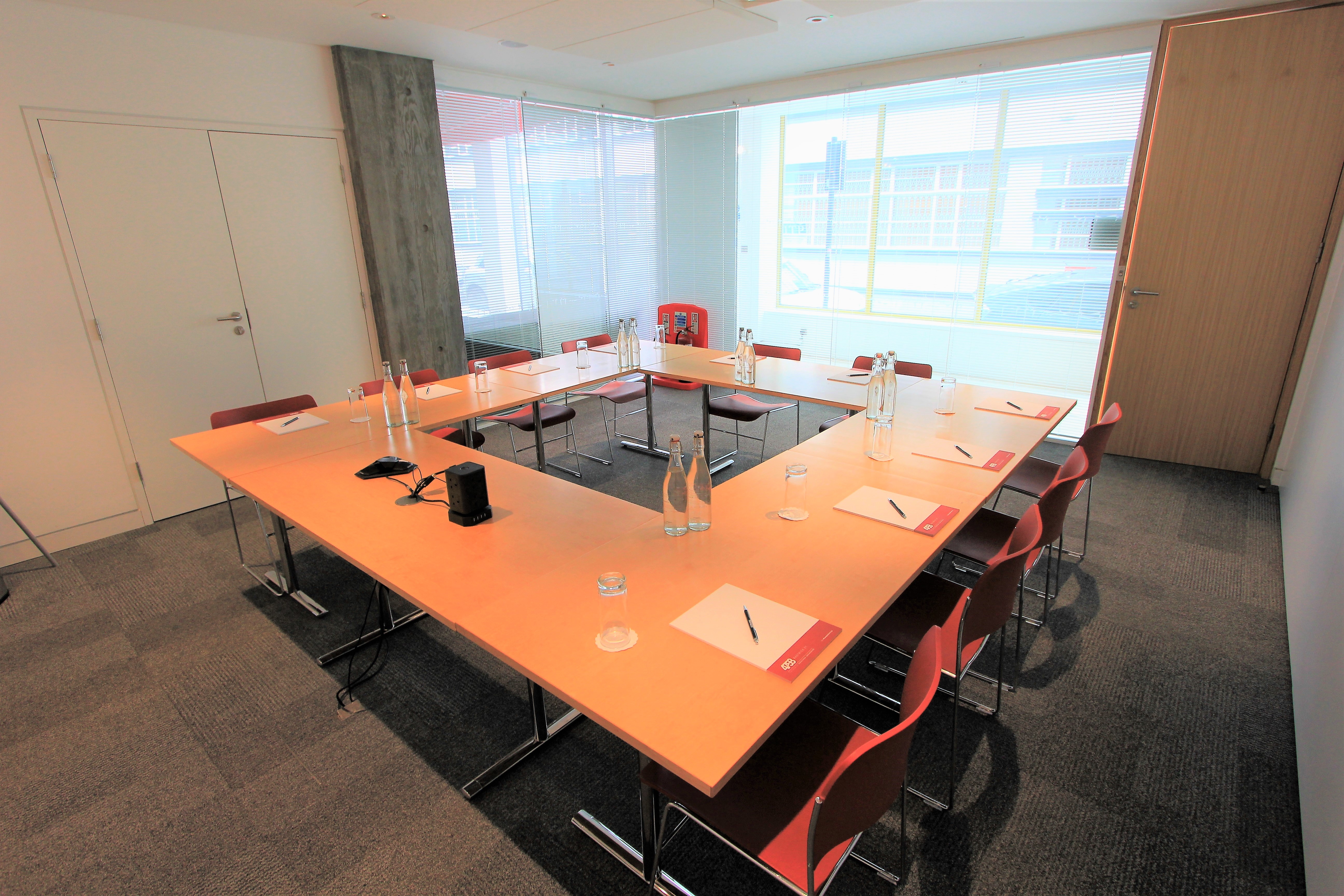 Modern meeting room with large table and red chairs for collaborative events.