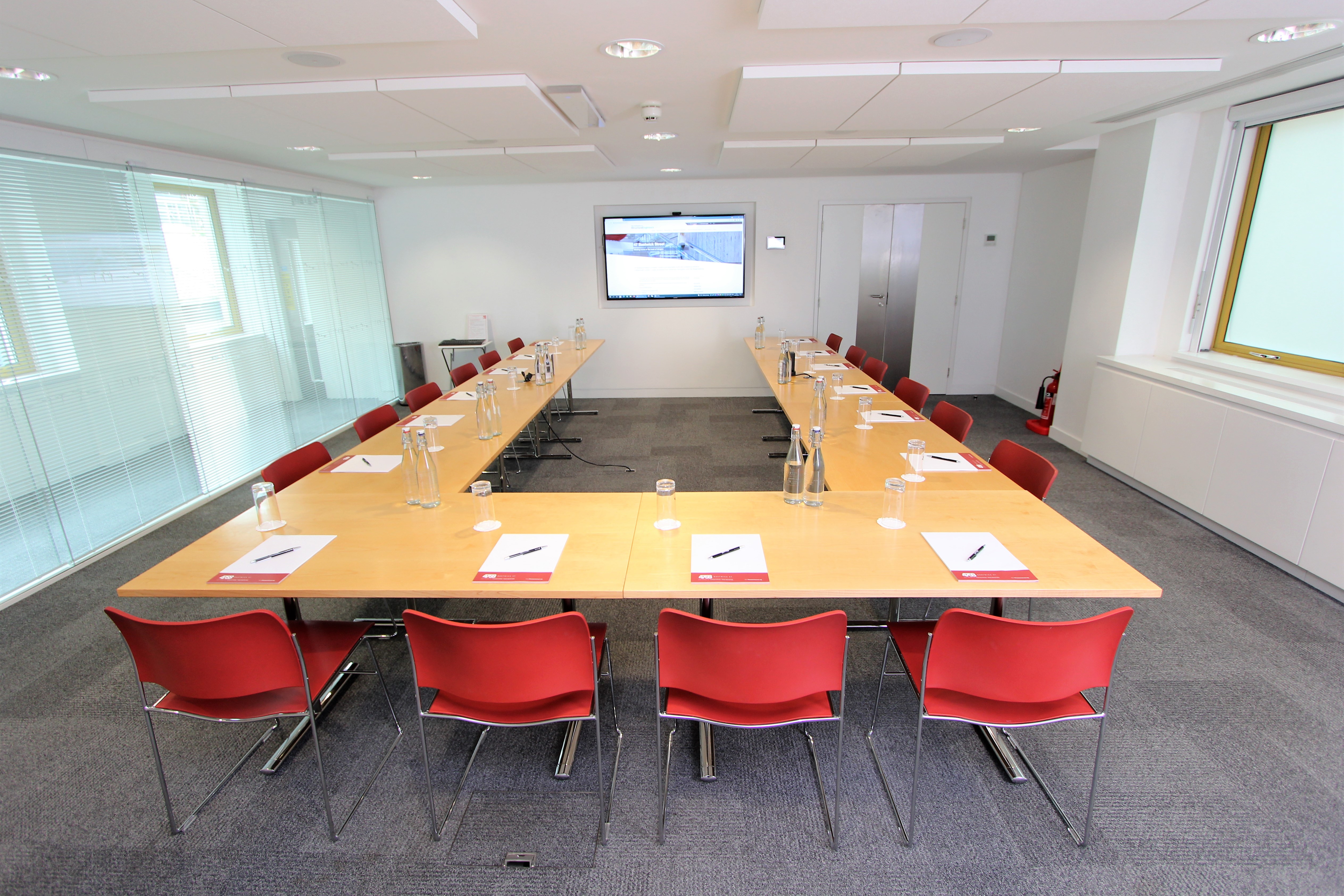 Modern conference room with red chairs, ideal for meetings and presentations.