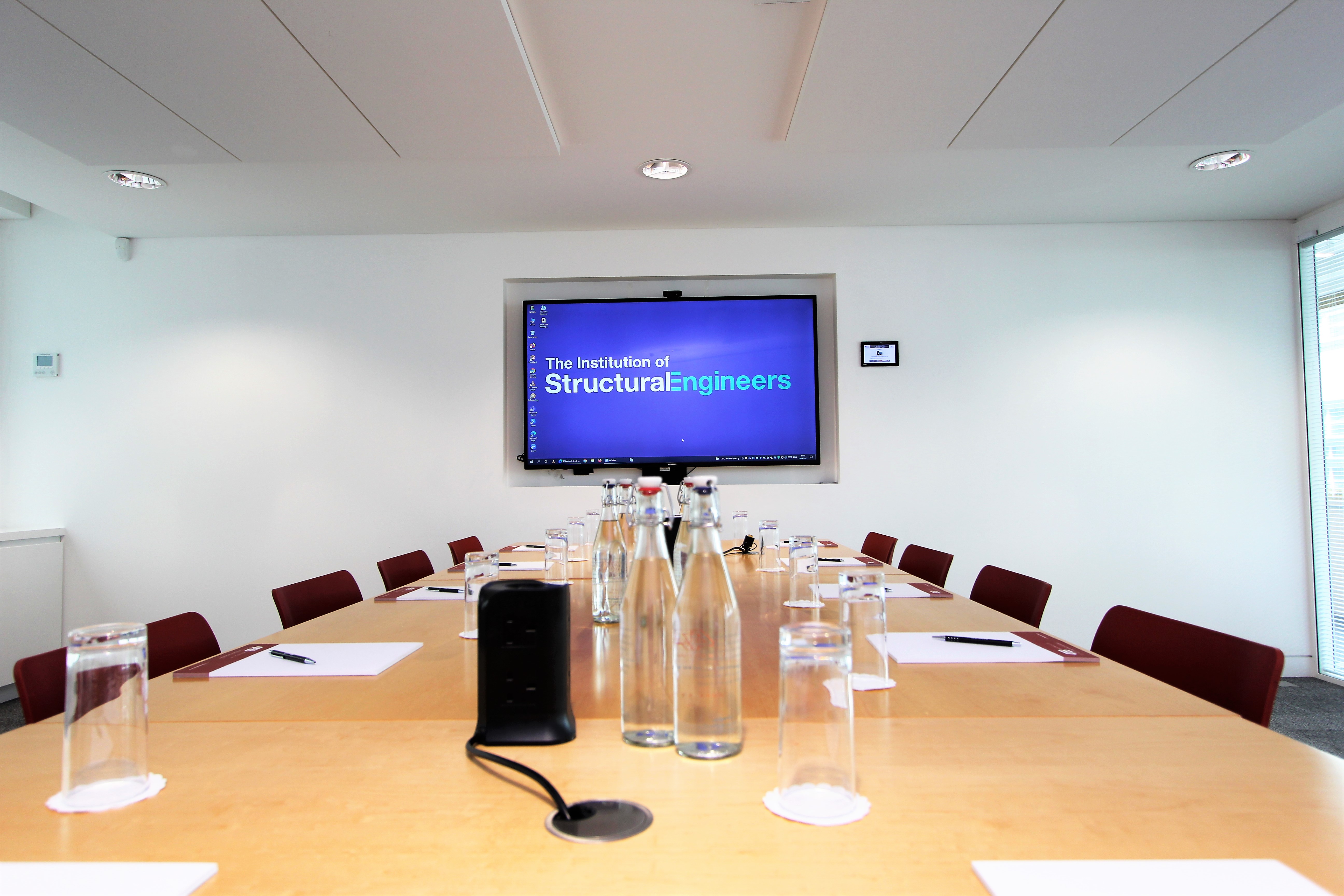 Modern conference room with large screen, ready for meetings and presentations.