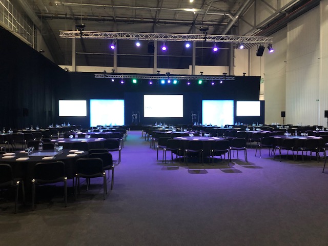 Conservation Hall at IWM Duxford set for a conference with round tables and stage.