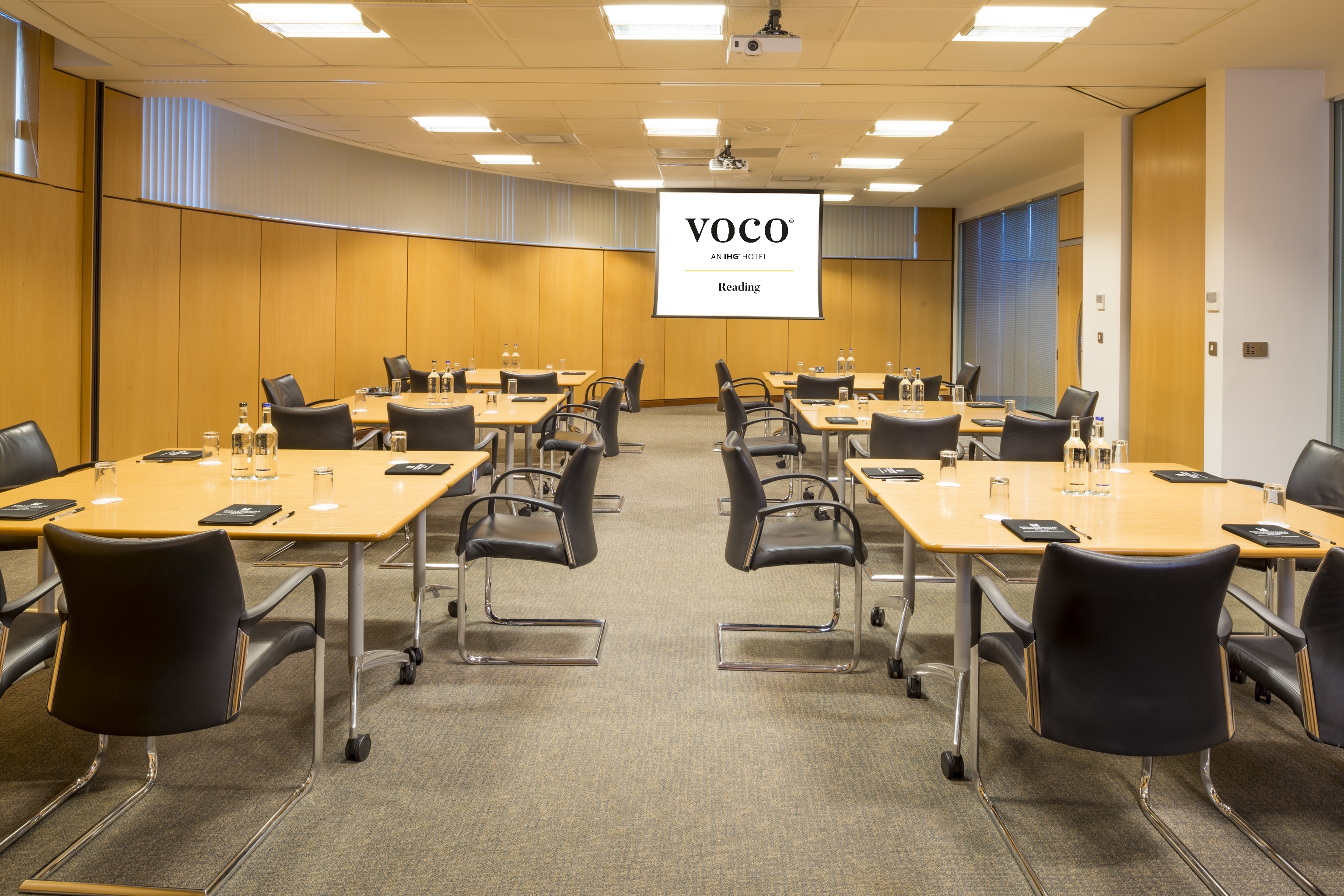 Kendrick and Abbey Suites meeting room with tables, chairs, and projector for events.