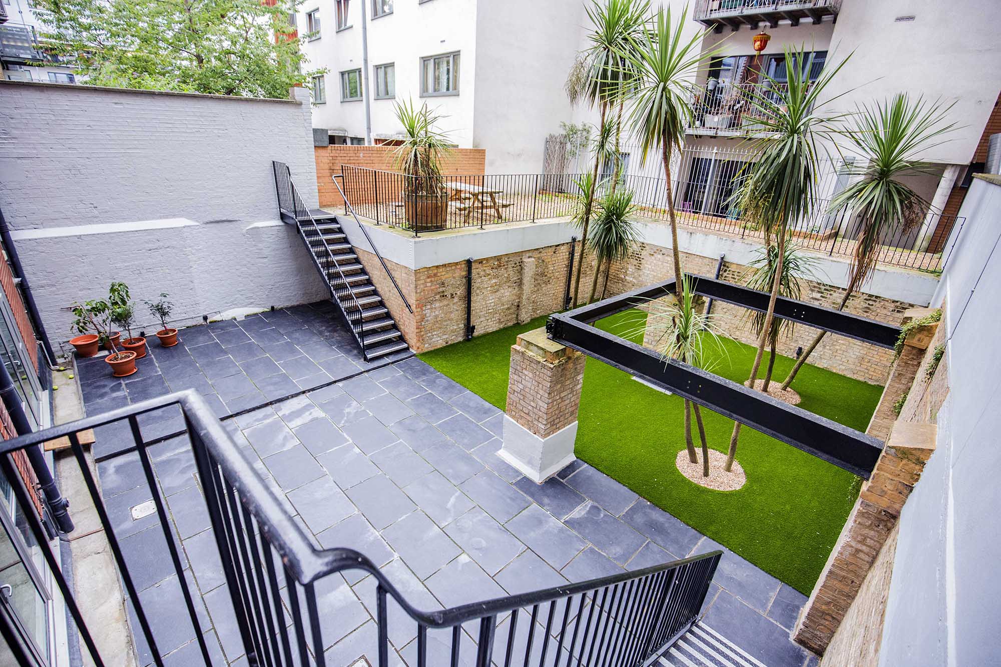 Versatile outdoor event space at House of Transformation with greenery and seating areas.