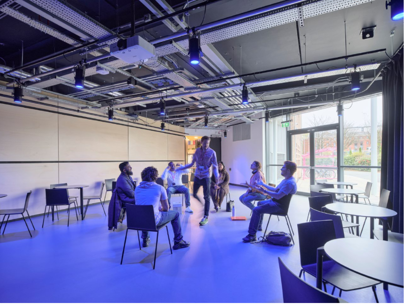 Modern meeting space with flexible seating and blue lighting for workshops and gatherings.