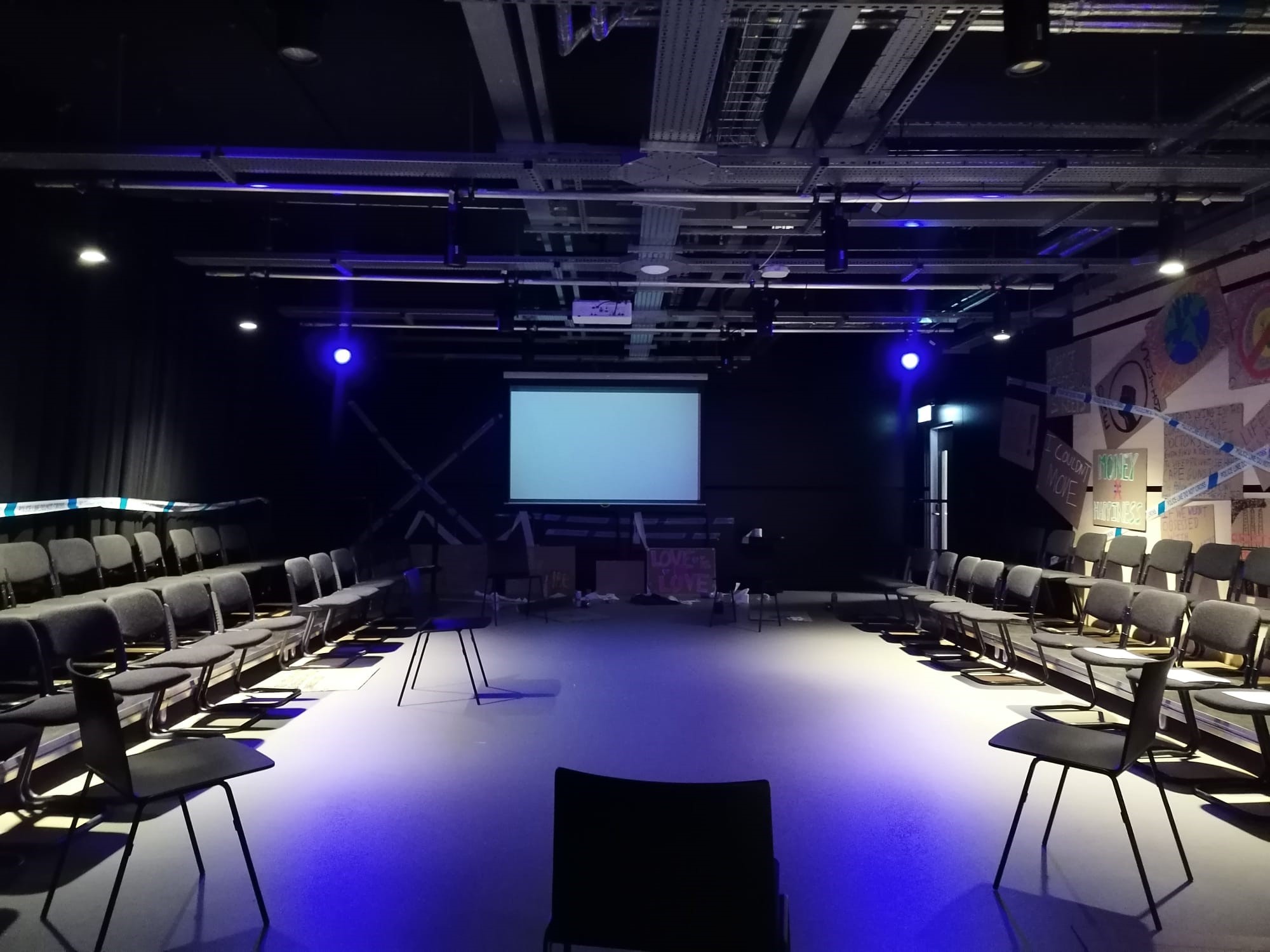 Versatile meeting space in Contact Theatre with semi-circle seating and projector screen.