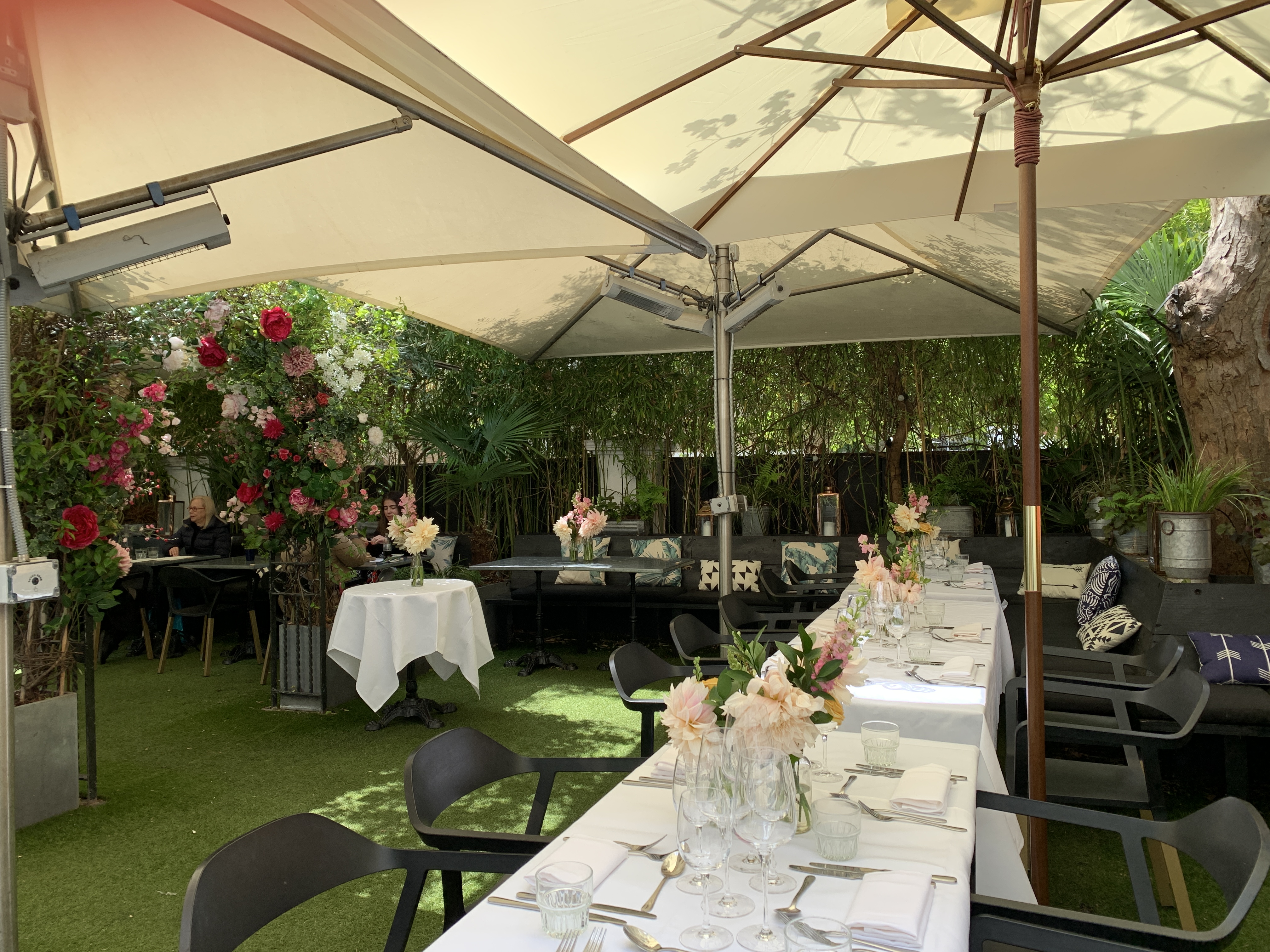 Elegant outdoor event space with long table, lush greenery for gatherings and celebrations.