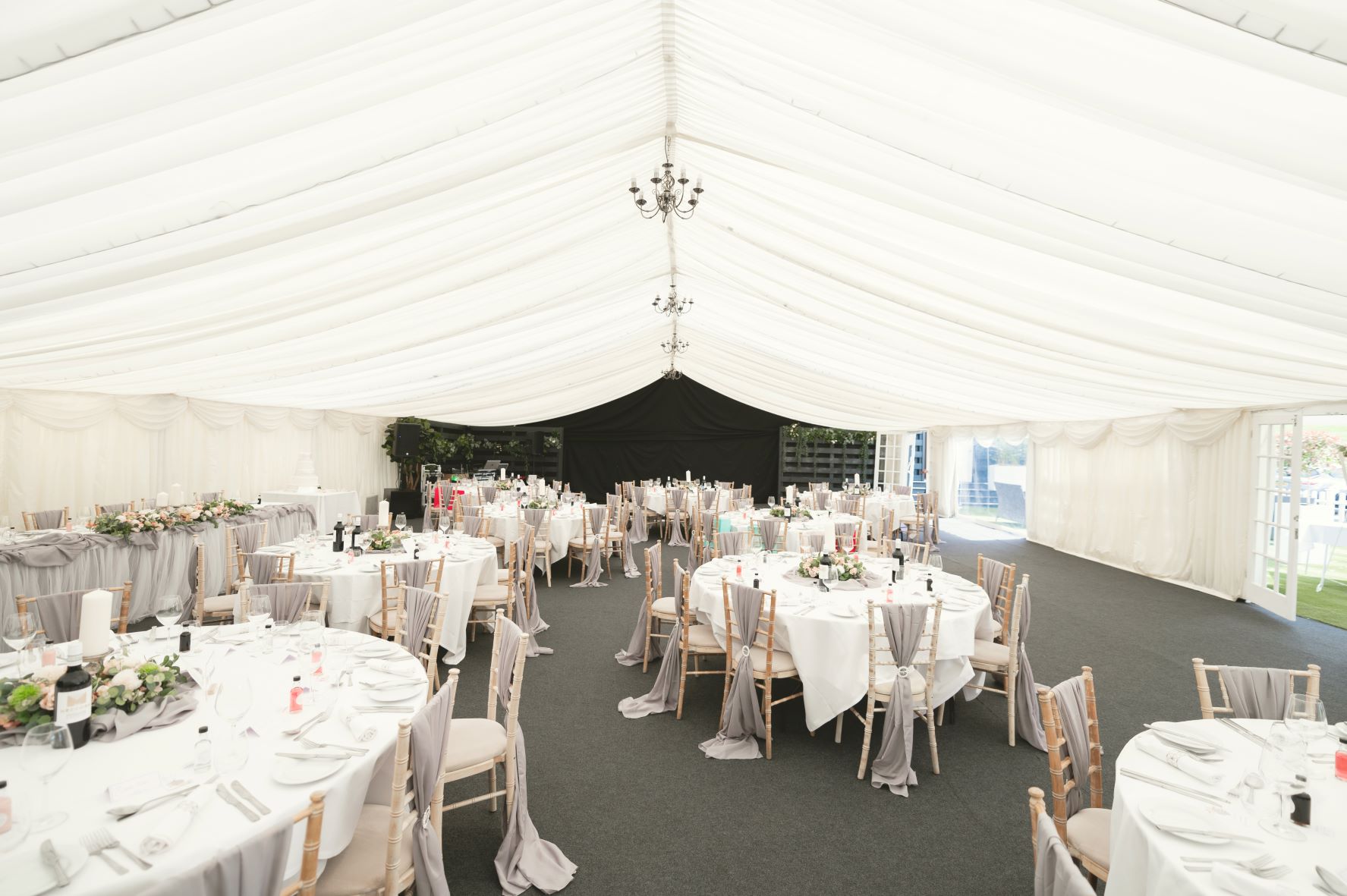 Elegant event tent at Cave Hotels, featuring round tables and floral centerpieces for weddings.