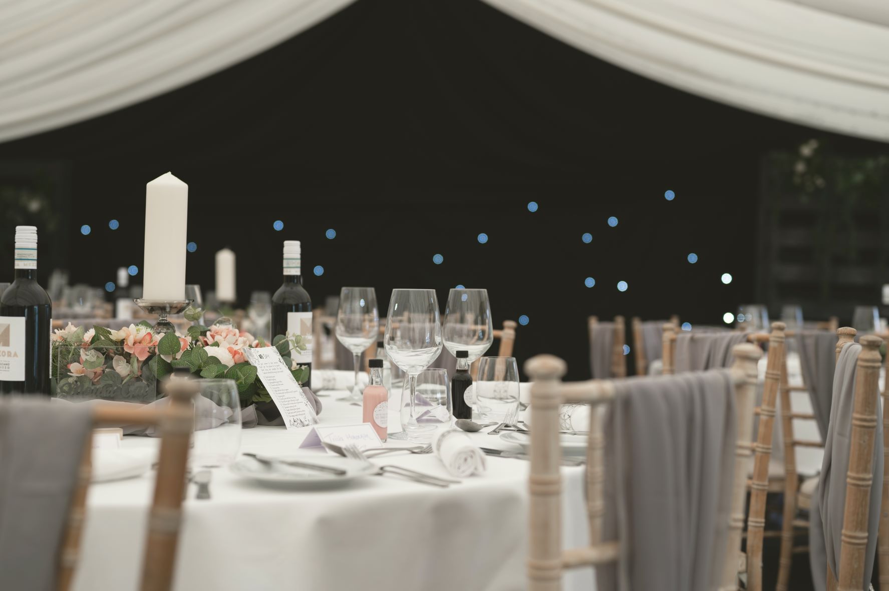 Elegant marquee dining area with floral centerpieces for weddings or corporate events.
