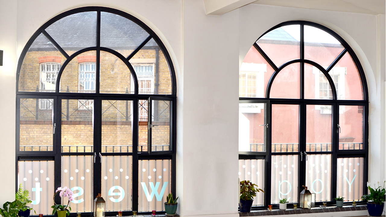 Bright yoga studio with arched windows, perfect for workshops and networking events.