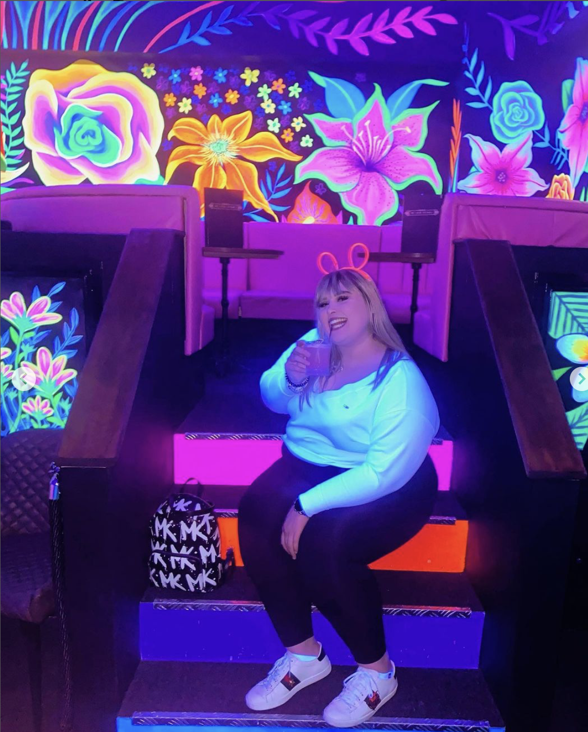 Vibrant neon-lit event space with floral backdrops for lively parties and gatherings.