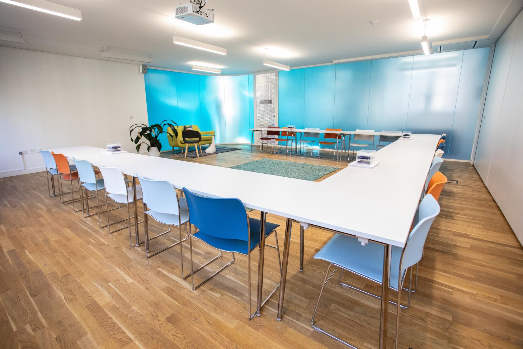 Modern meeting room with white table and colorful chairs for workshops and brainstorming.