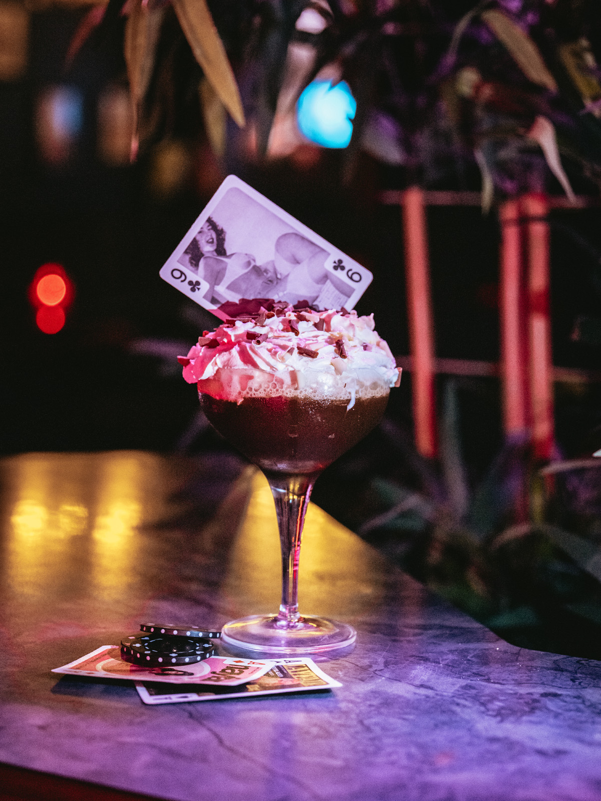 Creative cocktail with whipped cream and playing card in Disco Room for themed events.
