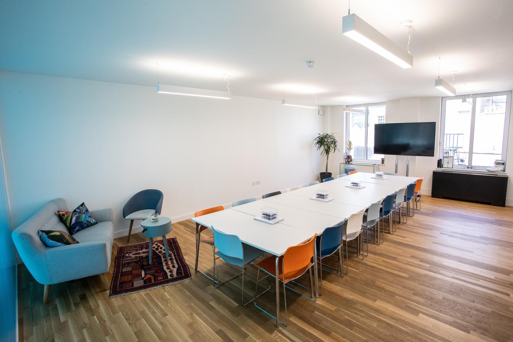 Modern meeting space with long table and colorful chairs for workshops and team gatherings.