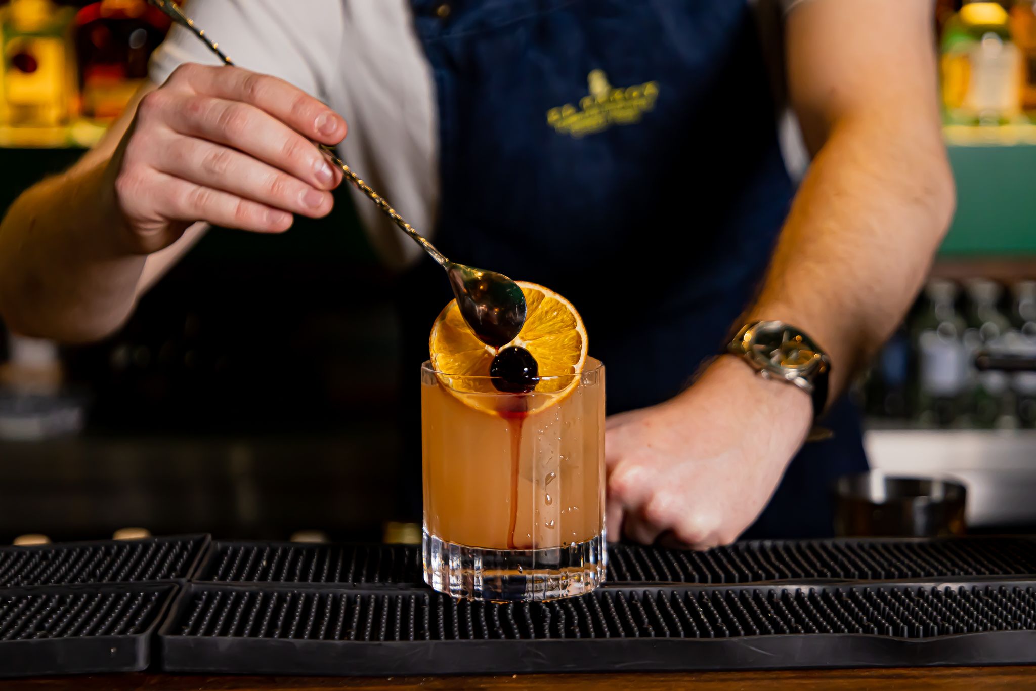 Bartender crafting a vibrant cocktail at El Ta'koy, perfect for event planning.