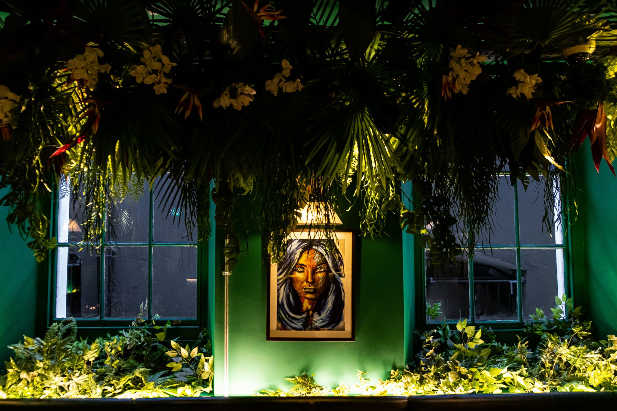 Vibrant event space at El Ta'koy with lush greenery and striking artwork for gatherings.