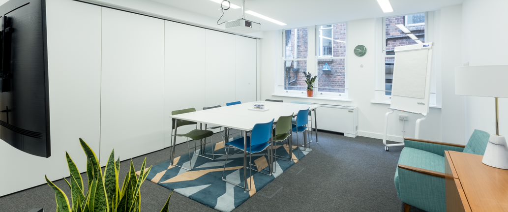 Modern meeting room with large table and colorful chairs, perfect for workshops.
