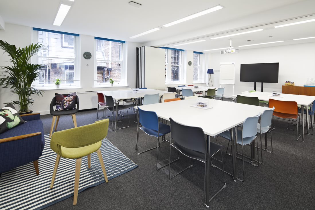 Modern meeting room with colorful chairs, ideal for workshops and team meetings.