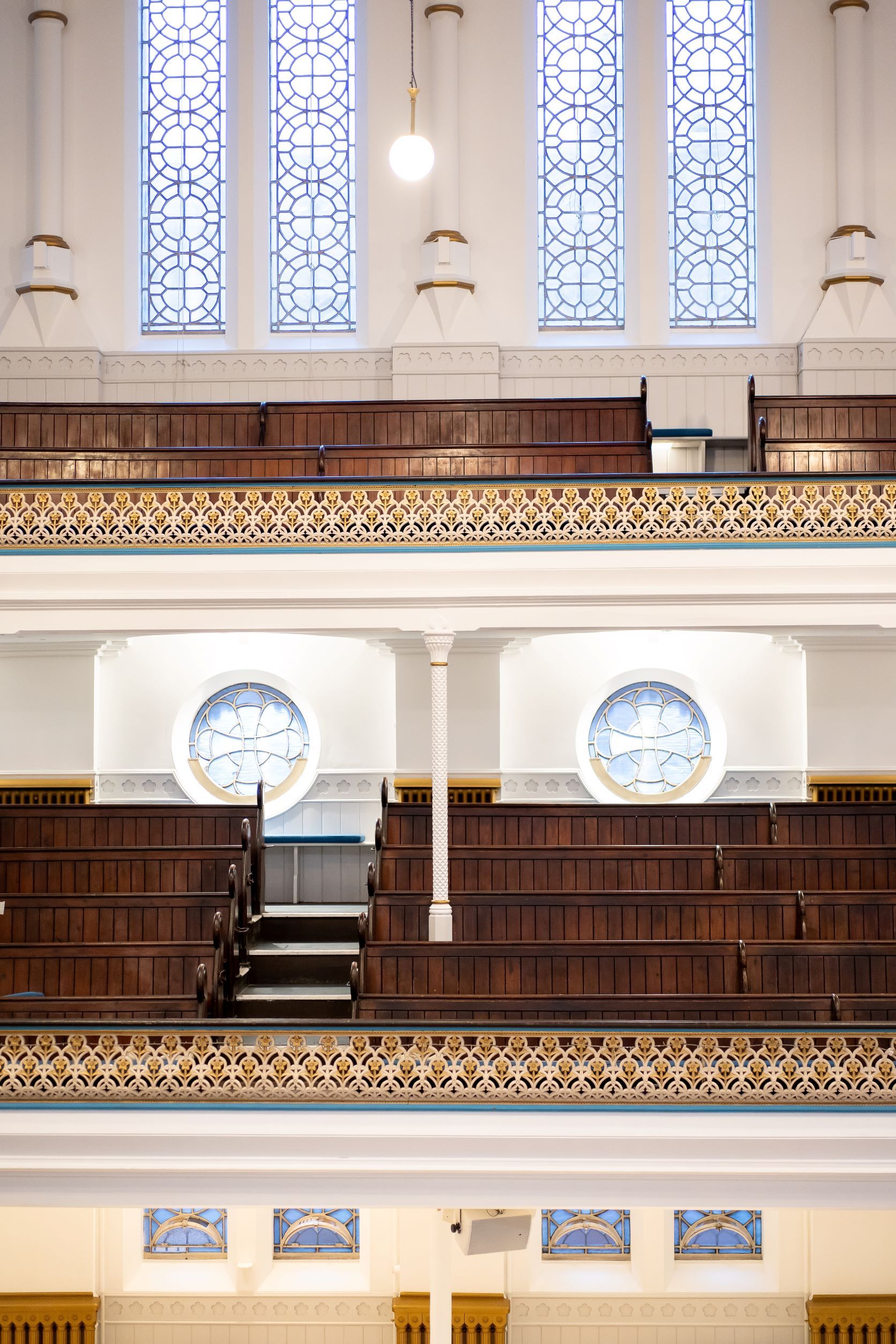 Elegant Westminster Chapel auditorium with wooden pews and stained glass for events.