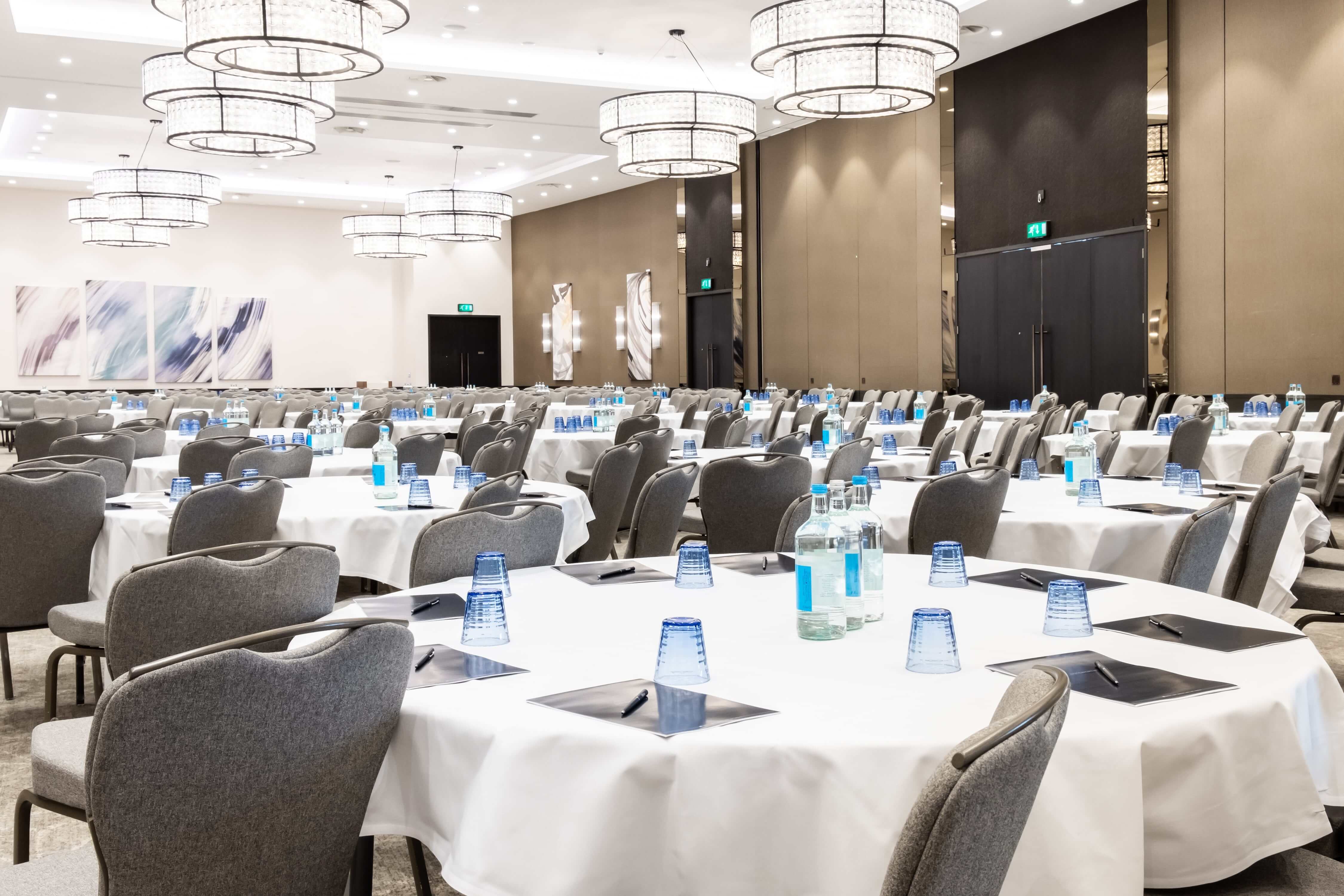 Ageas Ballroom at Hilton, elegant conference setup with round tables and modern lighting.