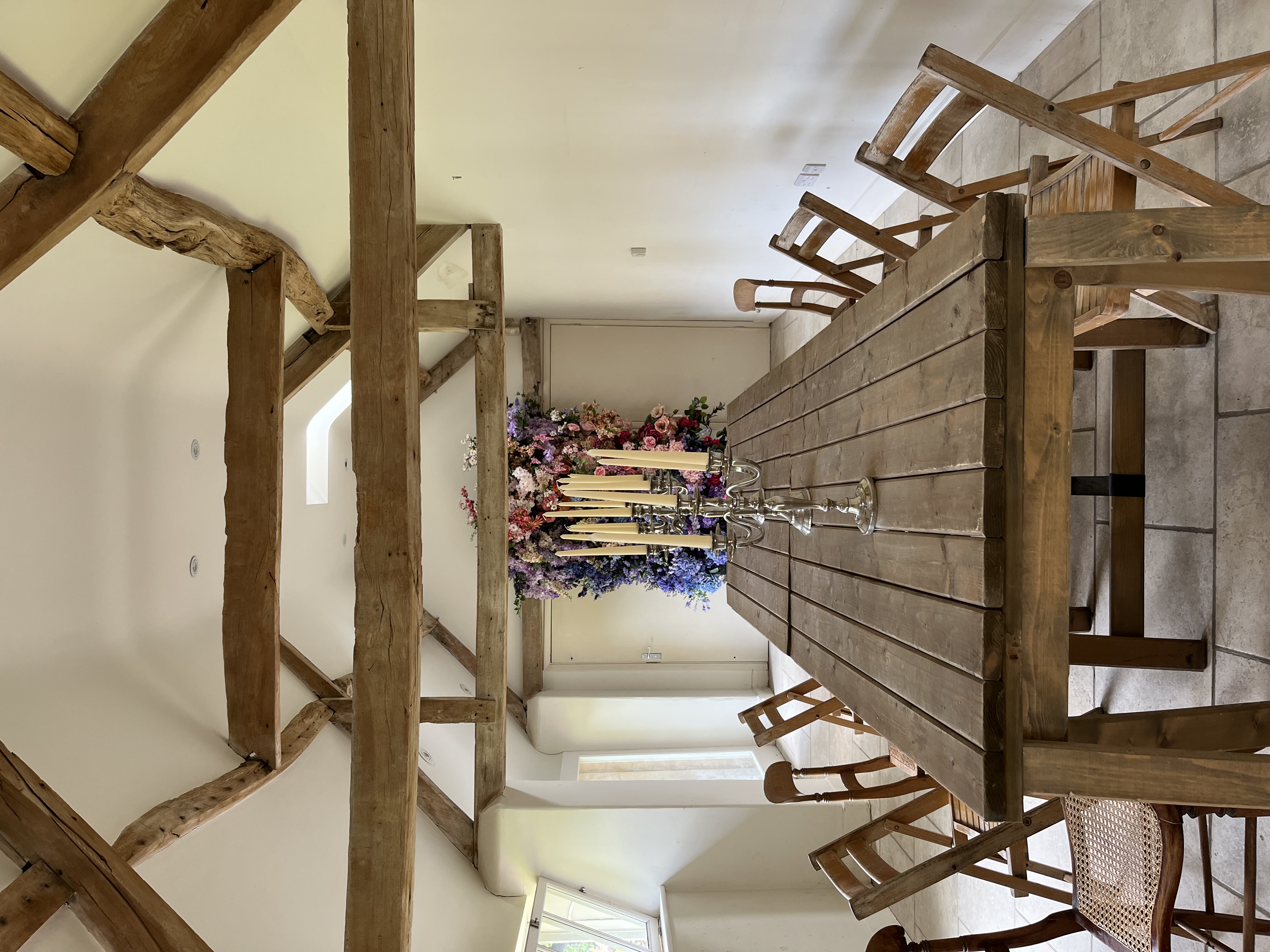 Rustic meeting space with wooden table, candles, and floral backdrop for workshops.