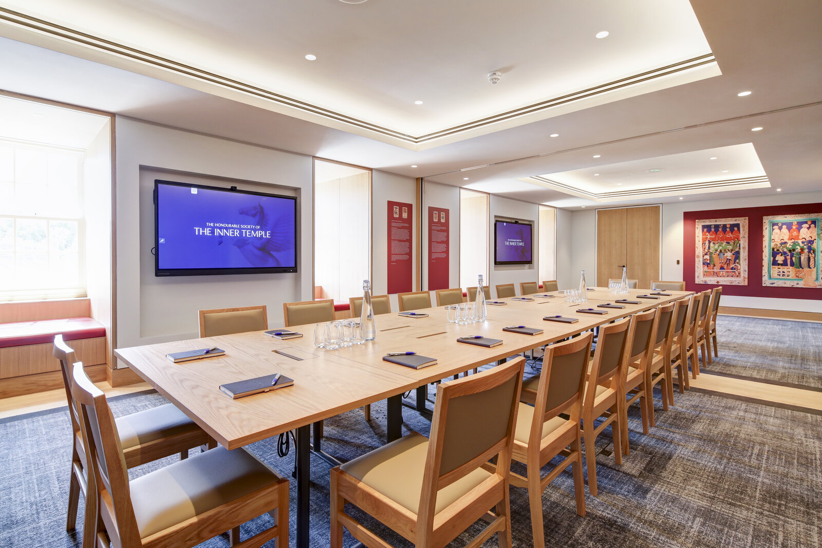 Modern meeting room with large table and dual screens for professional gatherings.