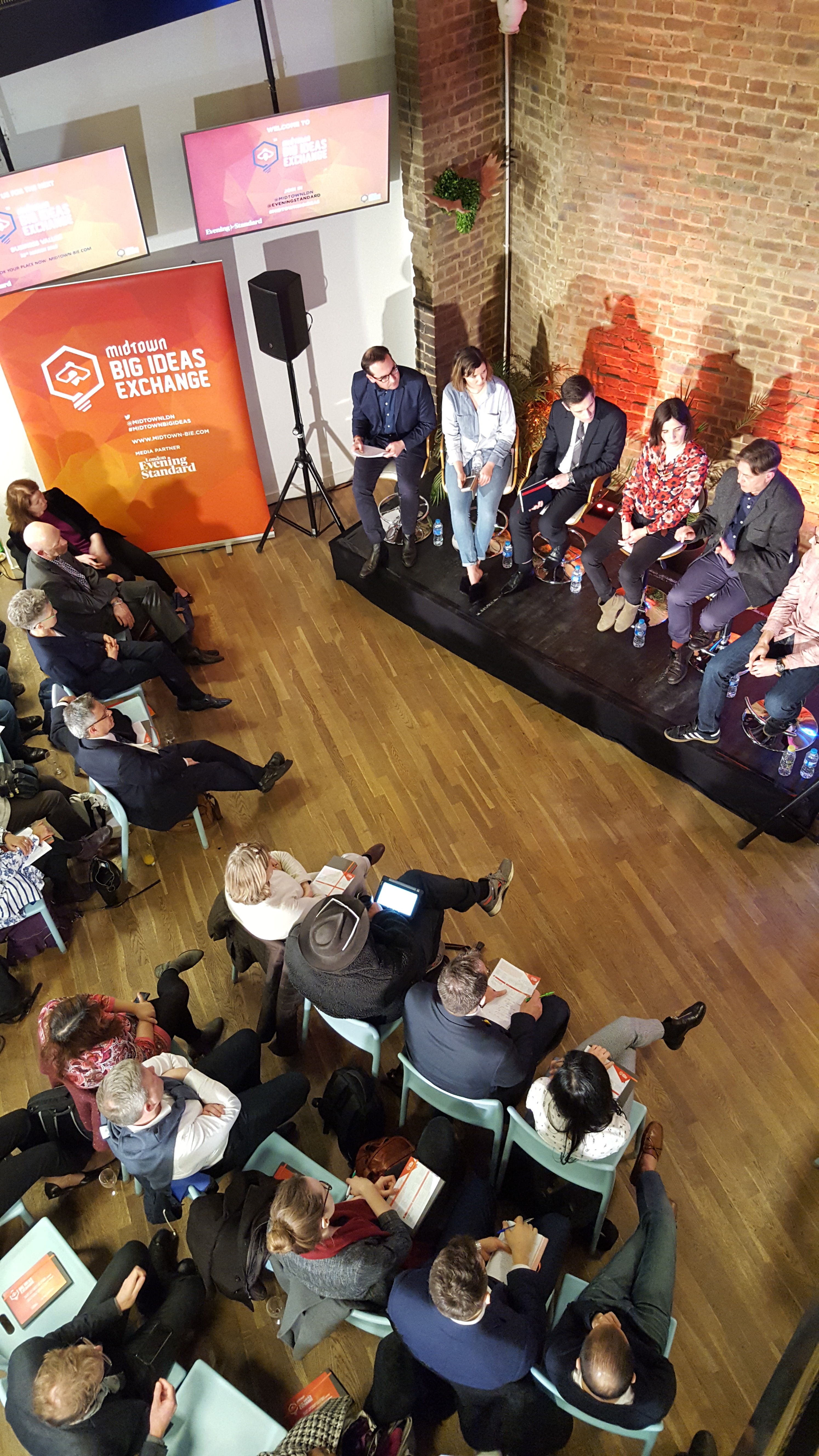 Dynamic panel discussion at Clerkenwell Kitchen with engaged audience in tiered seating.