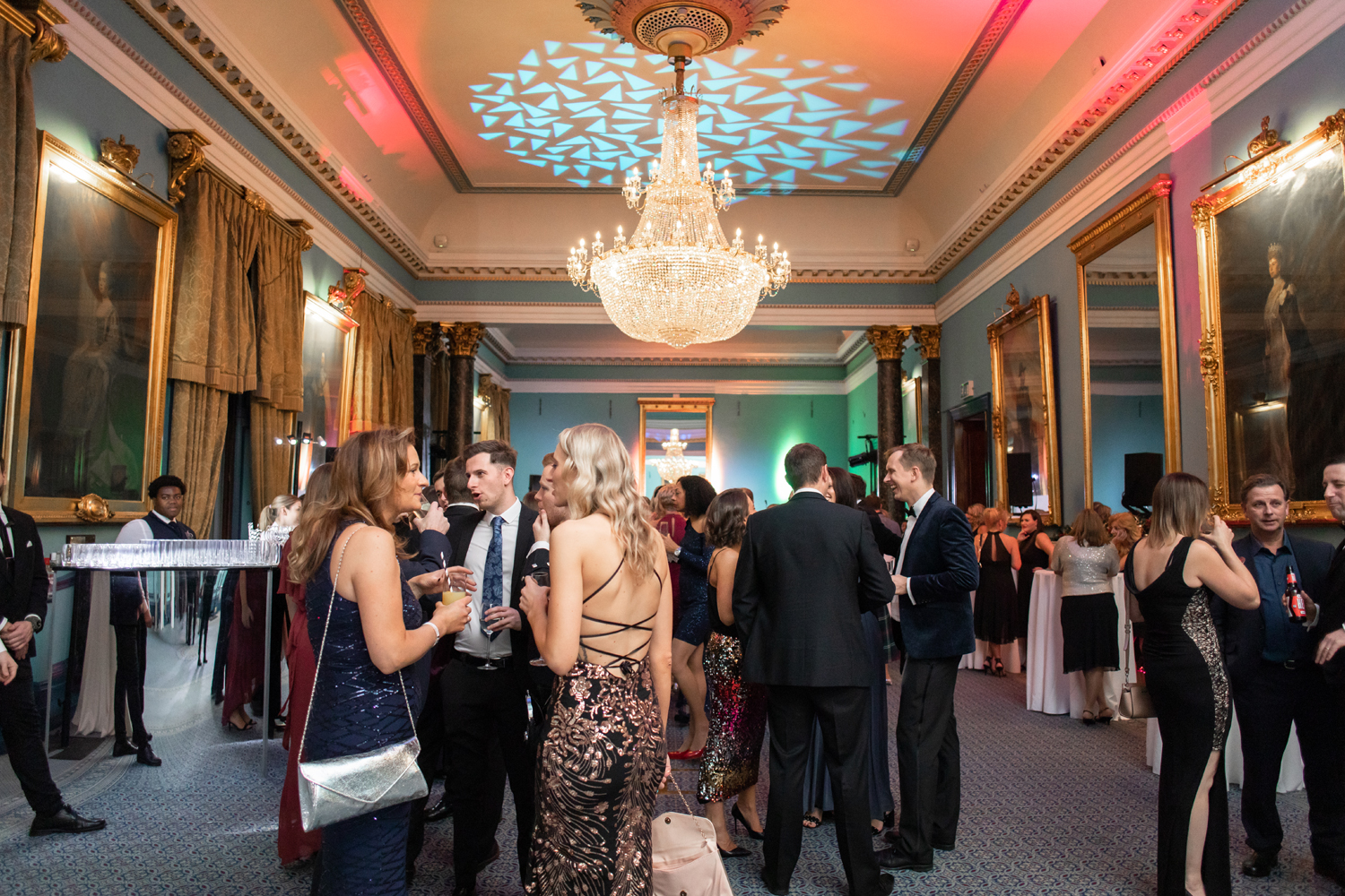 Elegant Christmas party at 116 Pall Mall with a luxurious chandelier and networking guests.