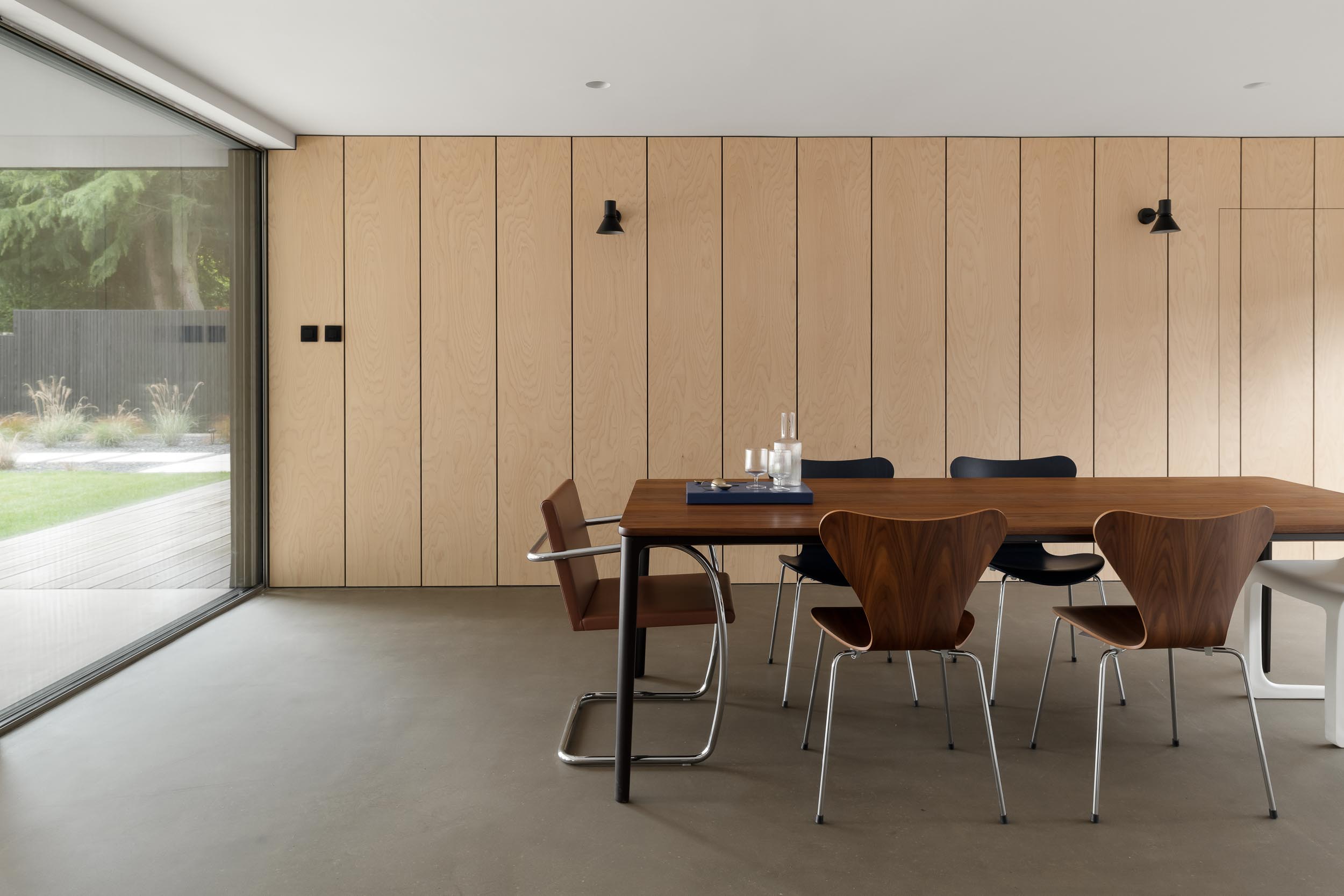 Modern minimalist meeting space with wooden table and glass wall for brainstorming sessions.