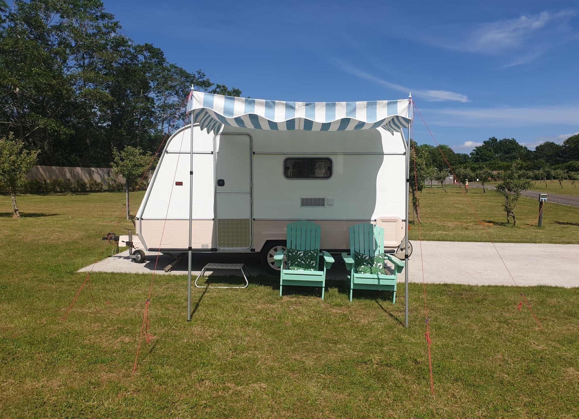 Vintage caravan with green chairs for unique outdoor events and gatherings.