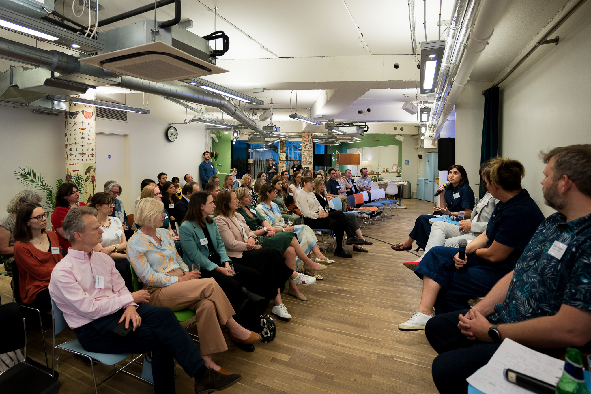 Panel discussion in modern event space with engaged audience and natural light.