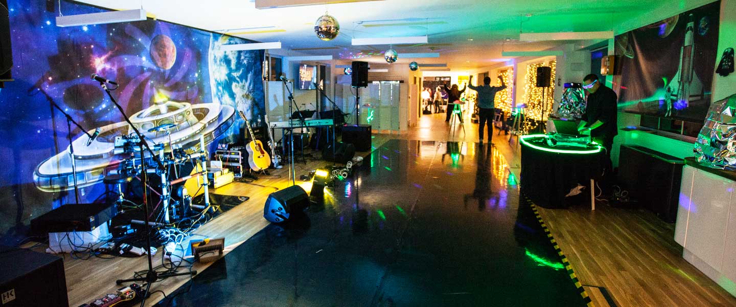 Vibrant event space at The Den, featuring a stage and colorful lighting for gatherings.