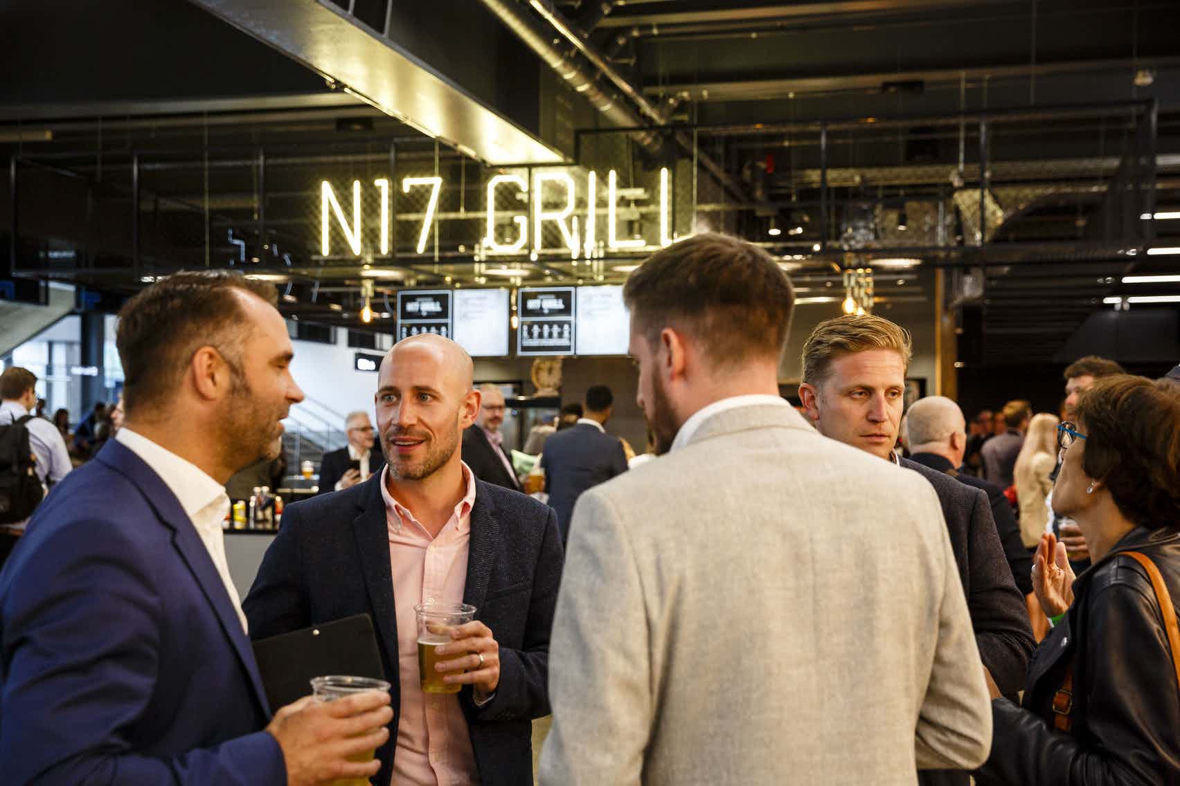 Vibrant networking event at Tottenham Hotspur Stadium's N17 GRILL bar area.