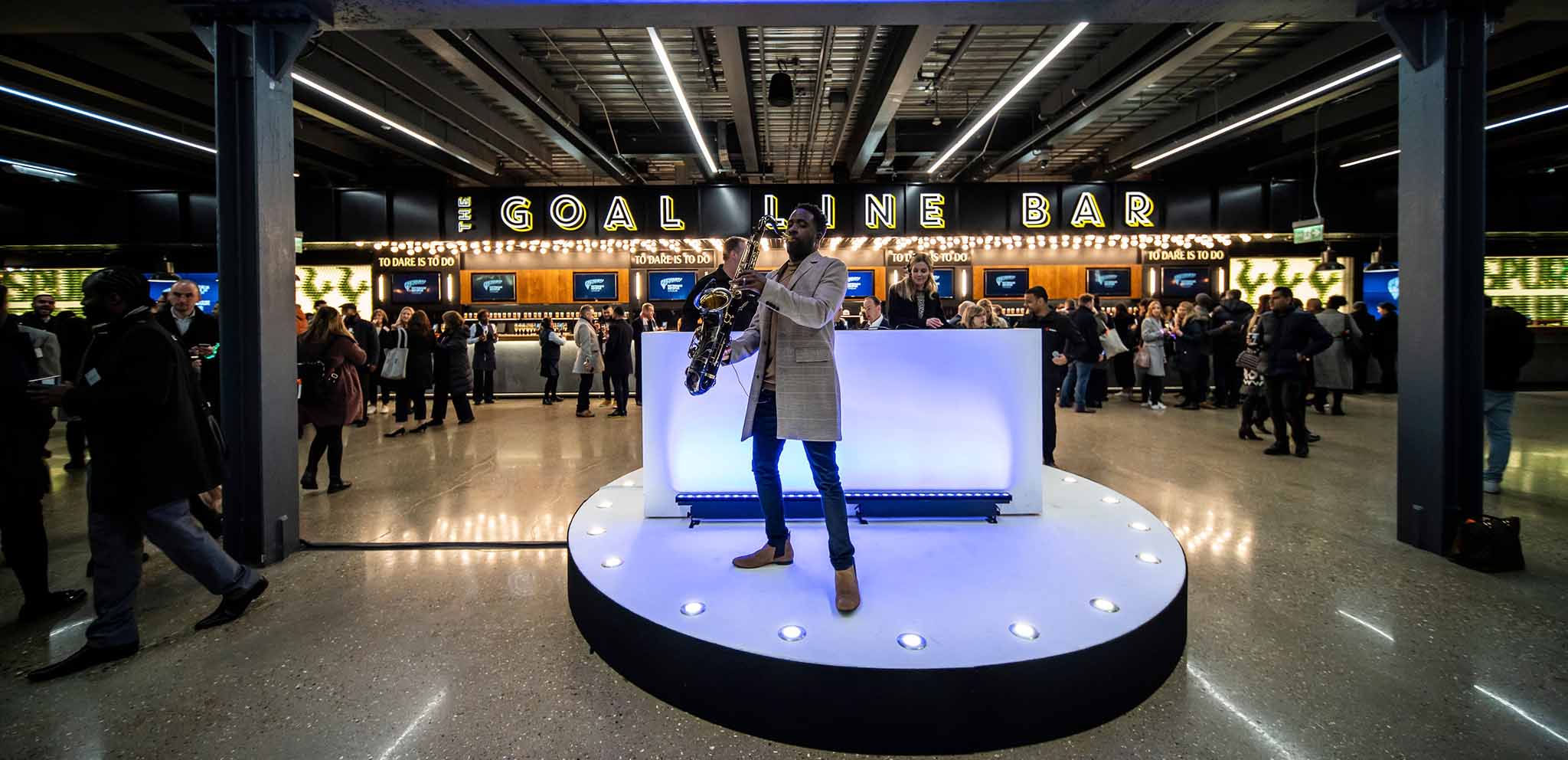 Saxophonist performing at Tottenham Hotspur Stadium's vibrant event space for networking.